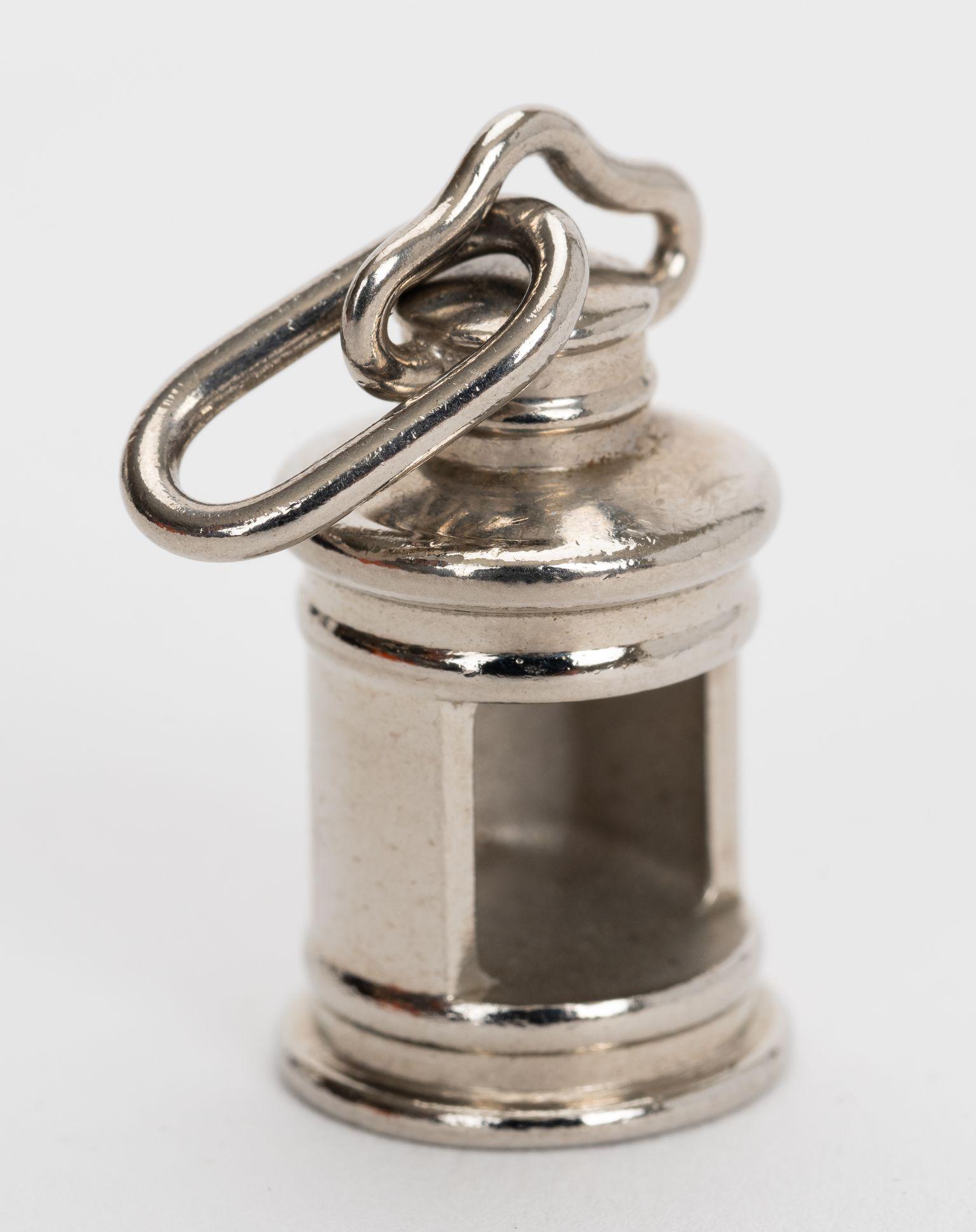 Die Hermès Curiosité Laterne Charm in Palladium Metall kommt mit original Samtbeutel und Box.