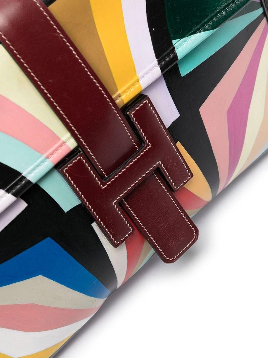 A true classic, the Jige has long been offered by Hermès. This beautiful burgundy box leather clutch bag is most distinctive by its graphic all-over geometric print, and features the iconic Jige fold-over top, front embossed leather “H” pull tab