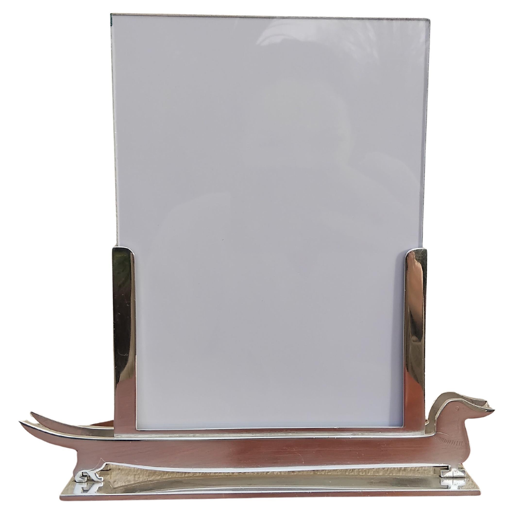 Exceptionnel et rare cadre photo Hermès authentique

Absolument magnifique, un véritable objet de collection pour les amoureux du teckel.

La base a la forme d'un teckel, le corps contenant des panneaux de verre au milieu desquels peuvent être