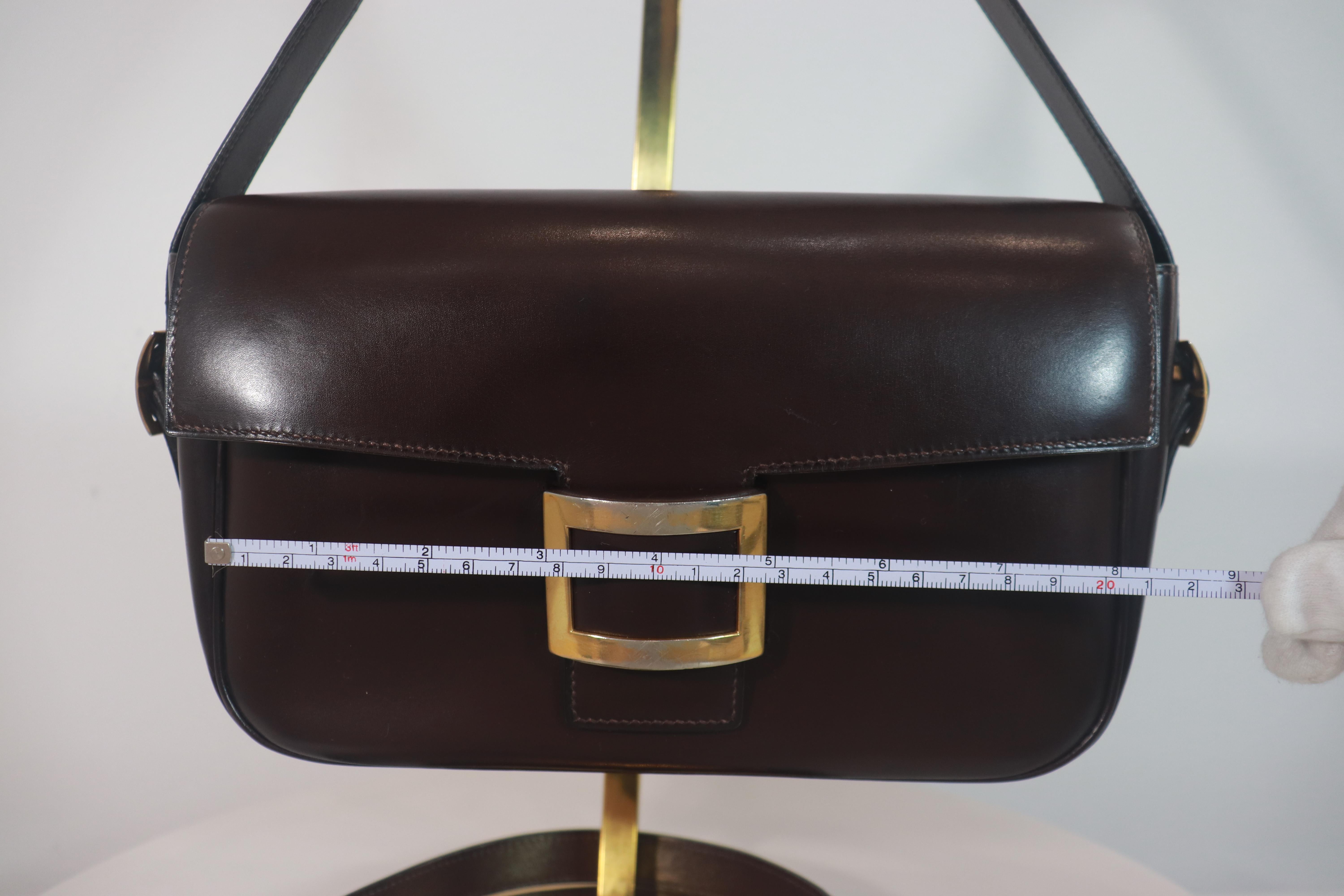 Hermès dark brown leather crossbody bag with gold buckle and additional adjustable strap. This crossbody bag is in 'LIKE NEW' condition. There are no significant flaws or wear areas to consider with this lovely crossbody bag. It had been very gently