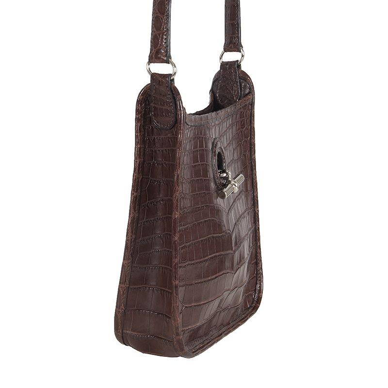 Hermès Vespa TPM Mini in matte brown crocodile. Opens with a long, metal piece which inserts into a buttonhole and functions as a clasp. Lined in brown calf leather. Has been carried and is in excellent condition. 

Height 18cm (7in)
Width 18cm