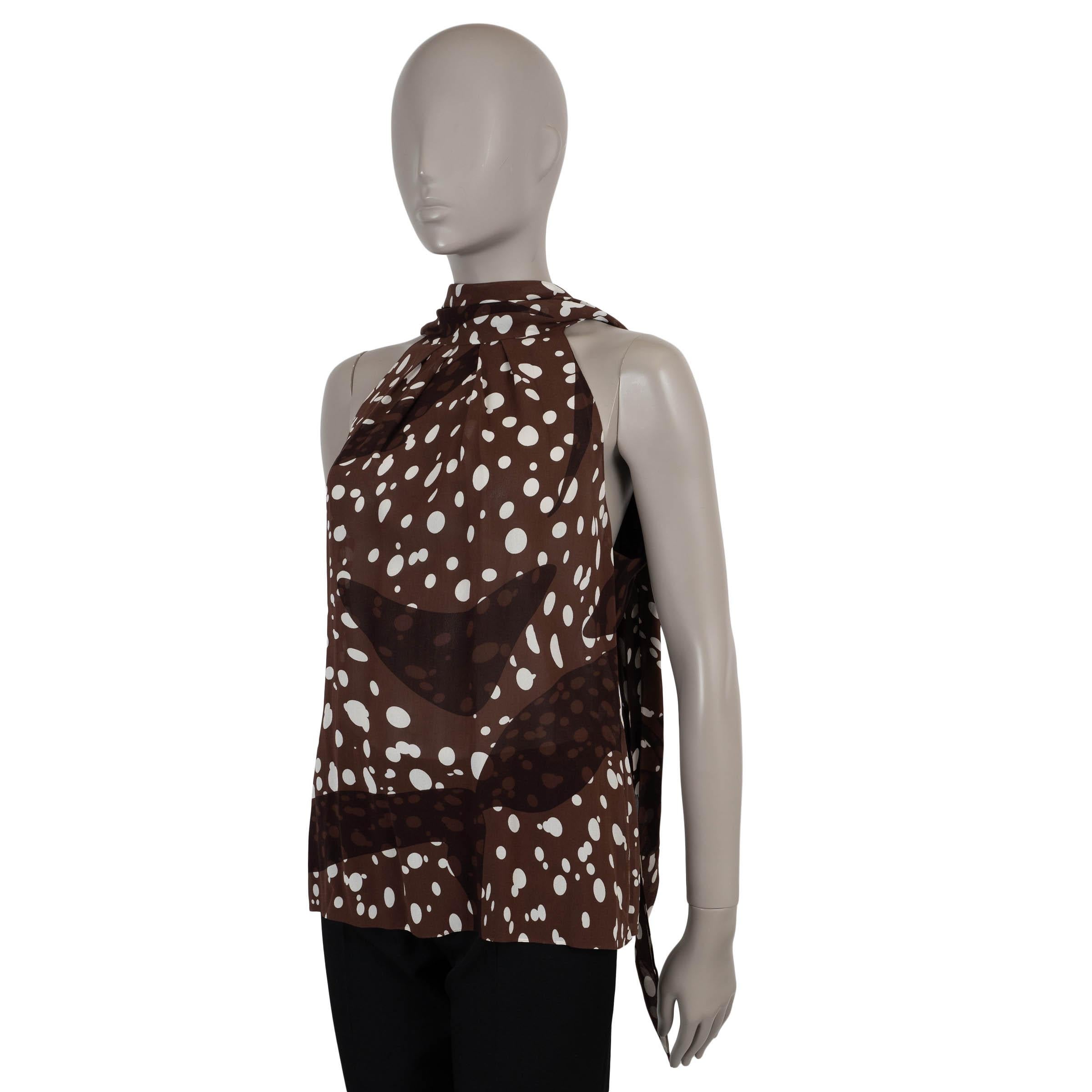 This 100% authentic Hermès blouse is crafted in chocolate brown chiffon silk with a white dotted print. The sleeveless, relaxed silhouette features a halter neckline that ties behind the neck and a keyhole with button closure at the back.
