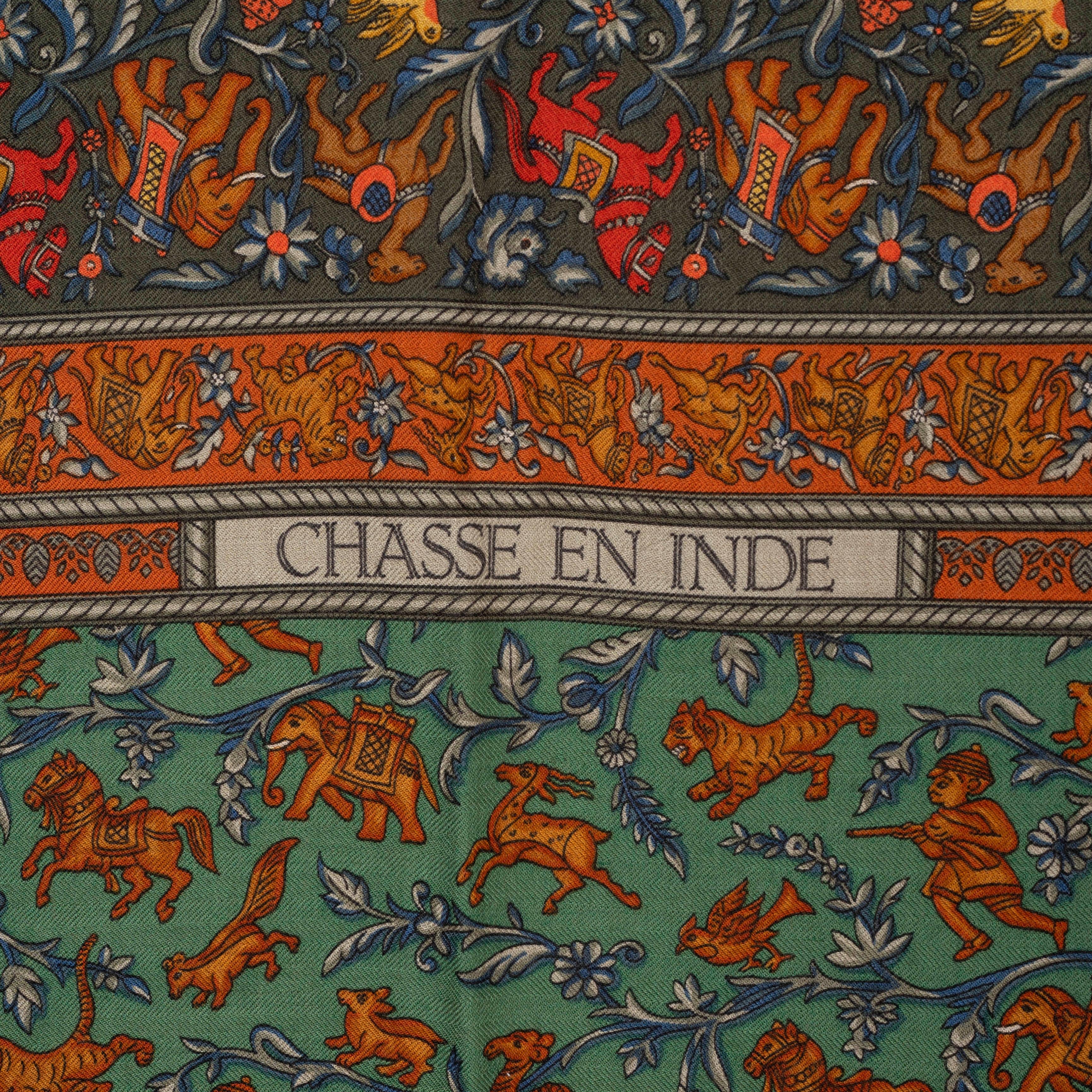 This 100% authentic Hermès Chasse en Inde 140 shawl, designed by Michel Duchene, is crafted from a luxurious blend of olive and green cashmere (65%) and silk (35%), with a rich dark green border. It features an intricately detailed, tiger