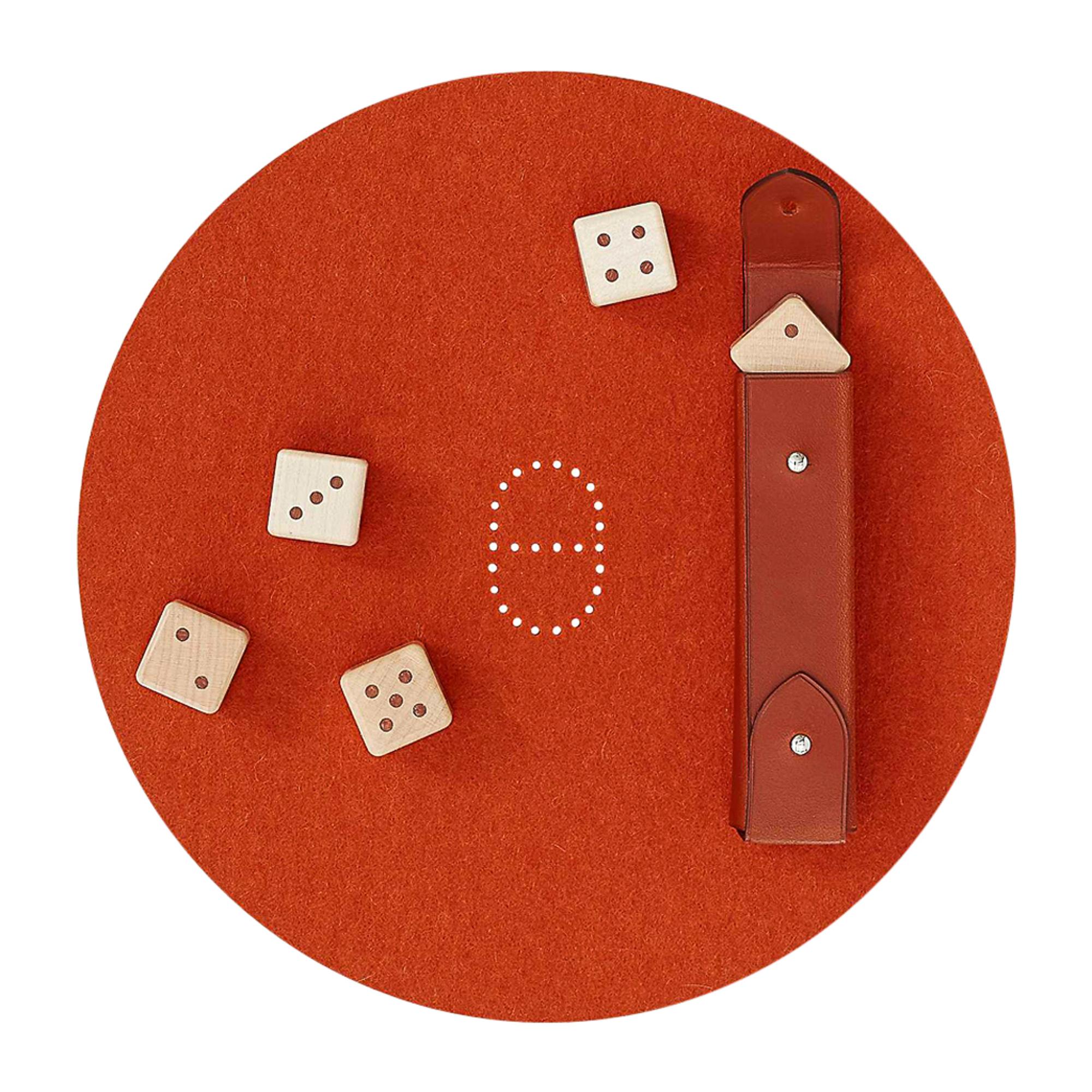 Mightychic offers an Hermes Declick Dice Game offered with a dash of luxury. 
Flanged bridle leather case marked with a saddle nail.
Maple marquetry dice. 
Rich Brique wool felt rug with Ancre perforated center.
Set includes score pad.
Comes with