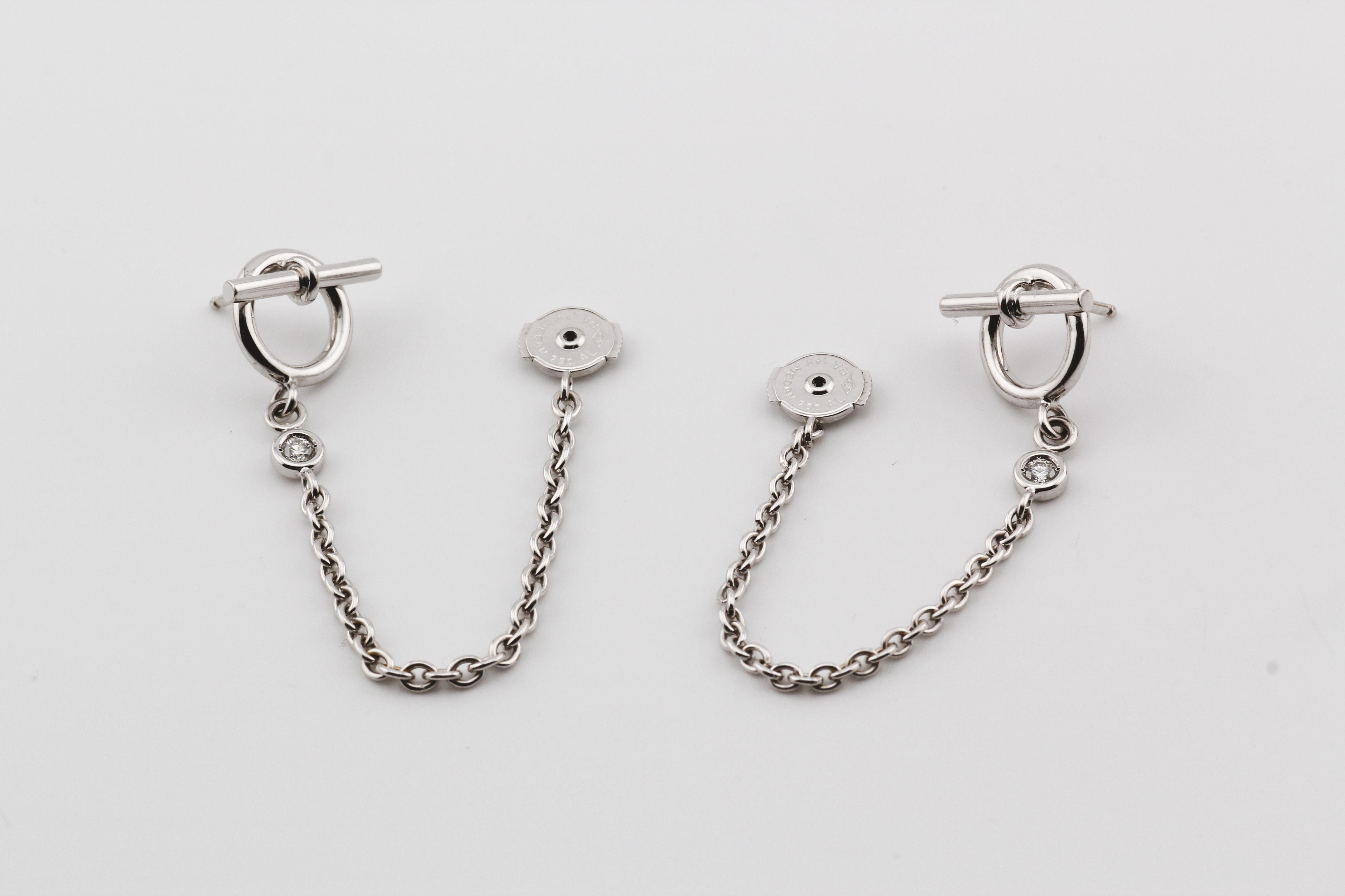 Introducing the Hermes Diamond 18K White Gold Dangling Toggle Stud Earrings—a sublime fusion of sophistication and modern allure. Crafted by the esteemed French luxury house, Hermes, these earrings showcase a harmonious combination of 18K white gold