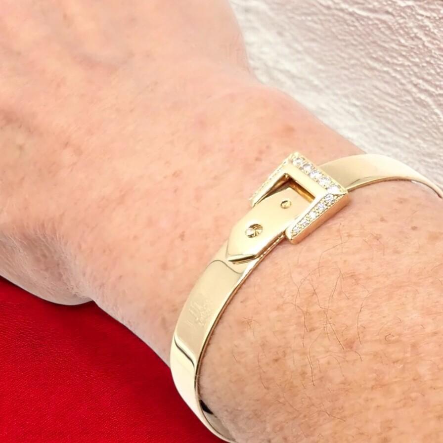 18k Yellow Gold Diamond Buckle Bangle Bracelet by Hermes.
The Hermès 18k Yellow Gold Diamond Buckle Bangle Bracelet is a luxurious statement piece, crafted from rich 18k yellow gold. 
It features a buckle-inspired design adorned with sparkling pavé