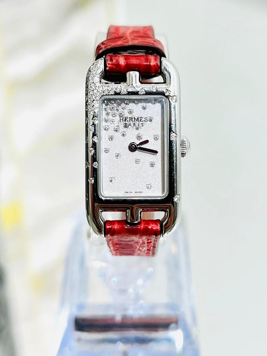 Hermes Diamond Nantucket Watch With Alligator Strap 

Flaunting brilliant white diamonds to the stainless steel case and the

face.  Set with 55 diamonds totalling .30cts. Bright red Alligator strap.

Quartz movement and pink buckle clasp closure.