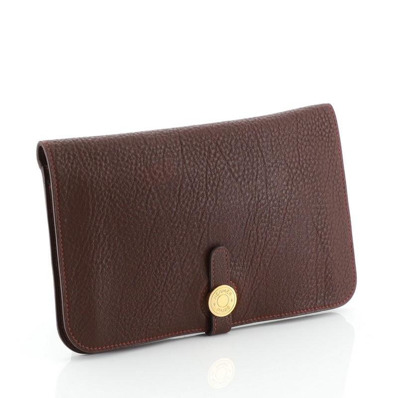 This Hermes Dogon Duo Combined Wallet Leather, crafted from Havane brown Evercalf leather, features gold hardware. Its clou de selle closure opens to a Havane brown Agneau leather leather interior with multiple slip pockets. Date stamp reads: A