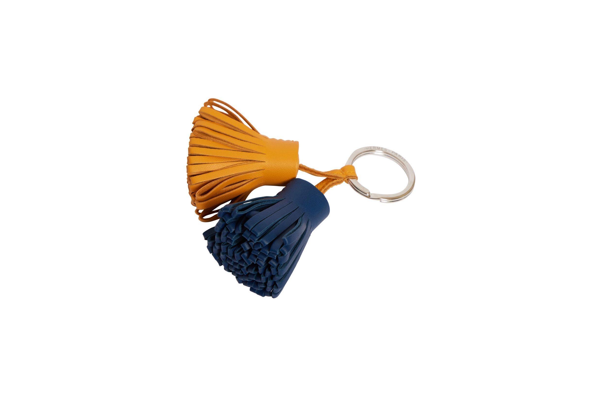 Hermes curry and deep blue leather double Carmen tassel keychain. The ring is crafted of palladium metal. The piece is brand new and comes with the original box, ribbon and shopping bag.