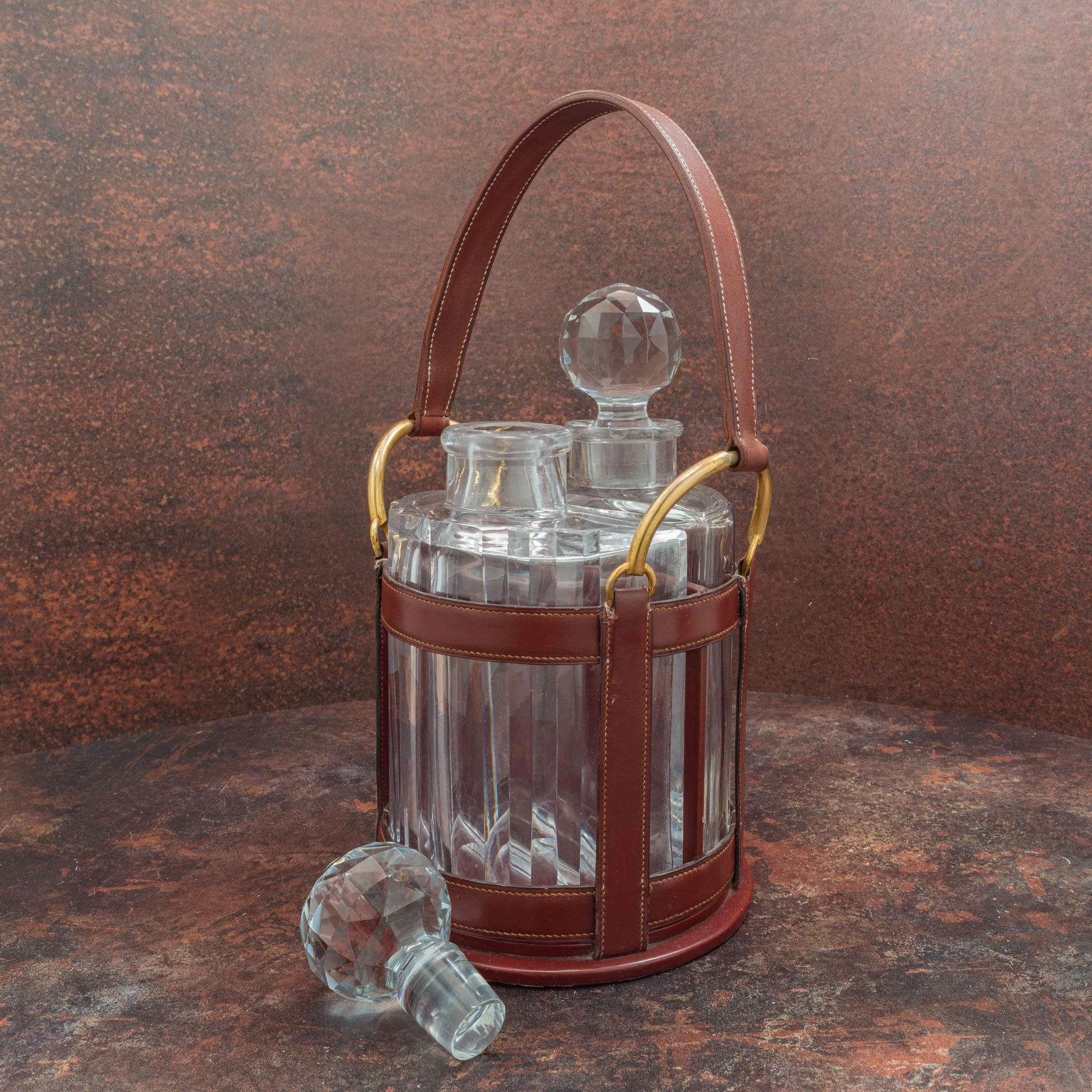 A fabulous drinks set by Hermès, circa 1955 to a design by Jacques Adnet, with cut crystal decanters. One of the decanters is by Baccarat, the other is unmarked and may be a replacement. Our master saddler has replaced the worn-out original handle
