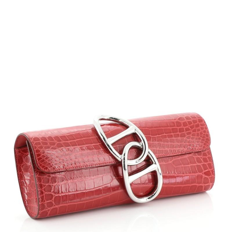 This Hermes Egee Clutch Niloticus Crocodile, crafted from Rouge Vif red shiny Niloticus crocodile skin, features oversized clasp closure, and palladium-tone hardware. Its flap opens to a red leather interior with slip pocket. Date stamp reads: Q