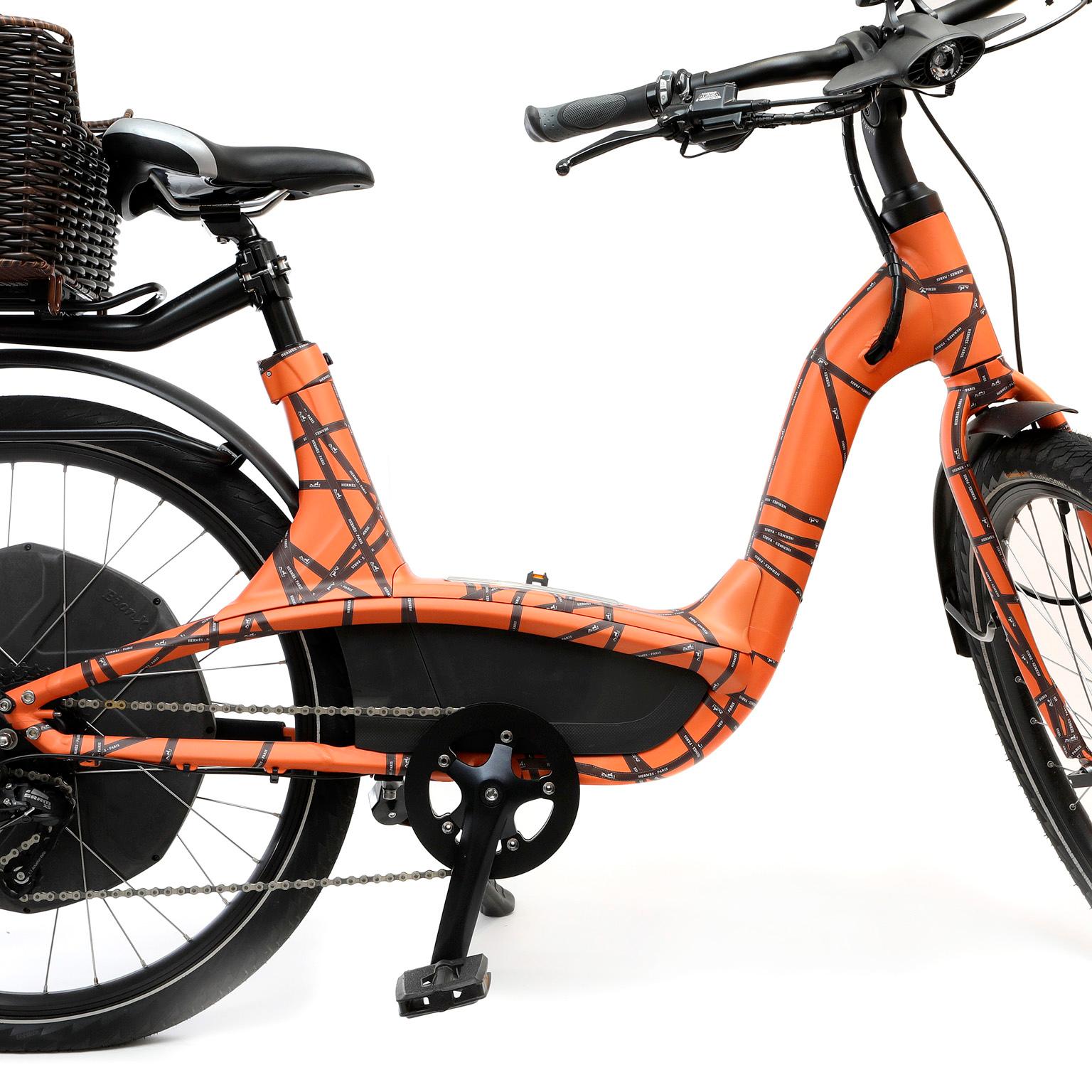 This authentic Hermès Electric Bike is in mint condition.  Orange frame with signature Hermès ribbon pattern.  Charming straw basket sits jauntily on the rear to carry the essentials. 
PBF 12236