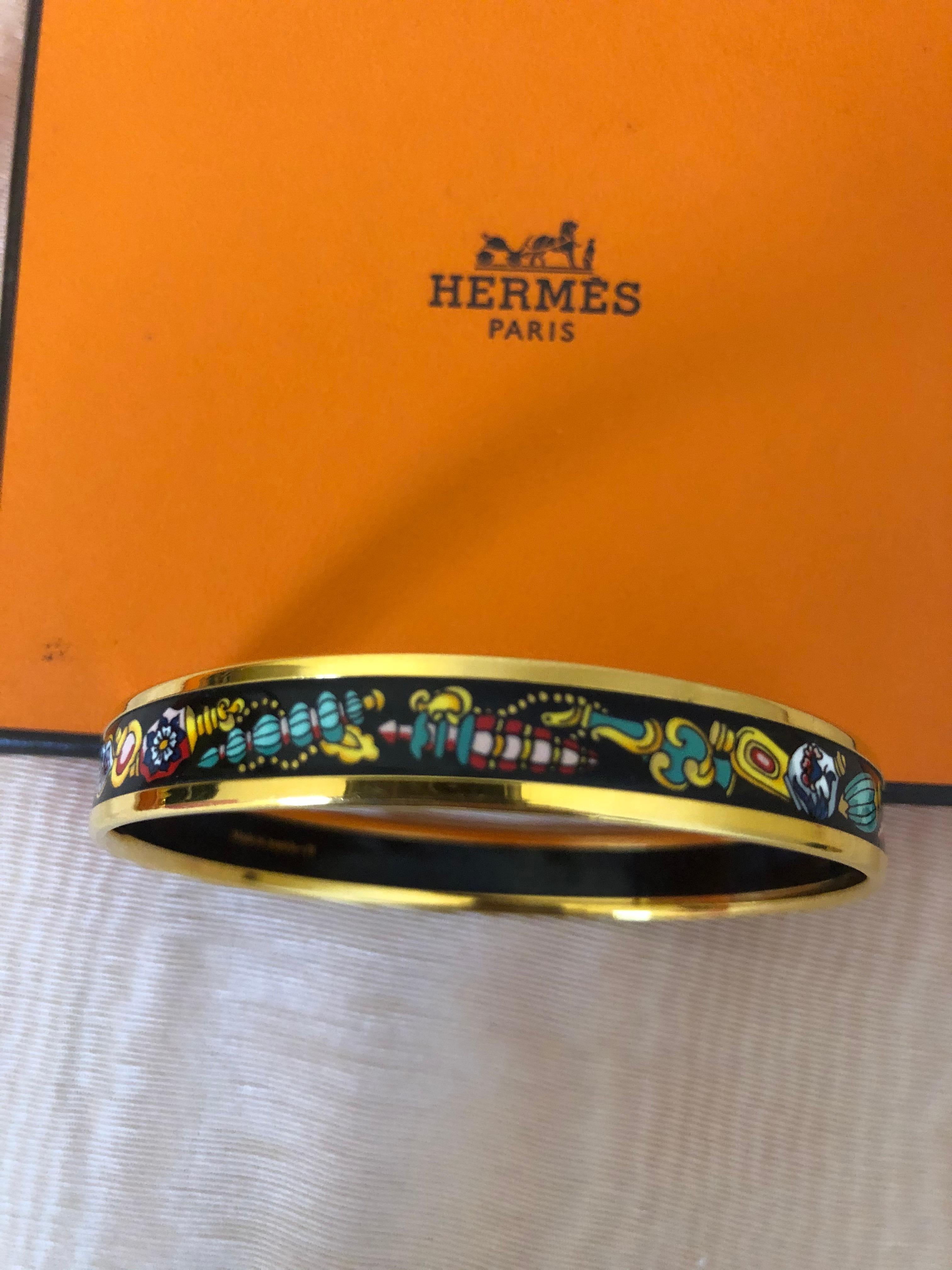 Lovely Hermes bangle depicting vintage perfume bottles in Palladium and enamel. This bracelet is in excellent condition and includes the box.