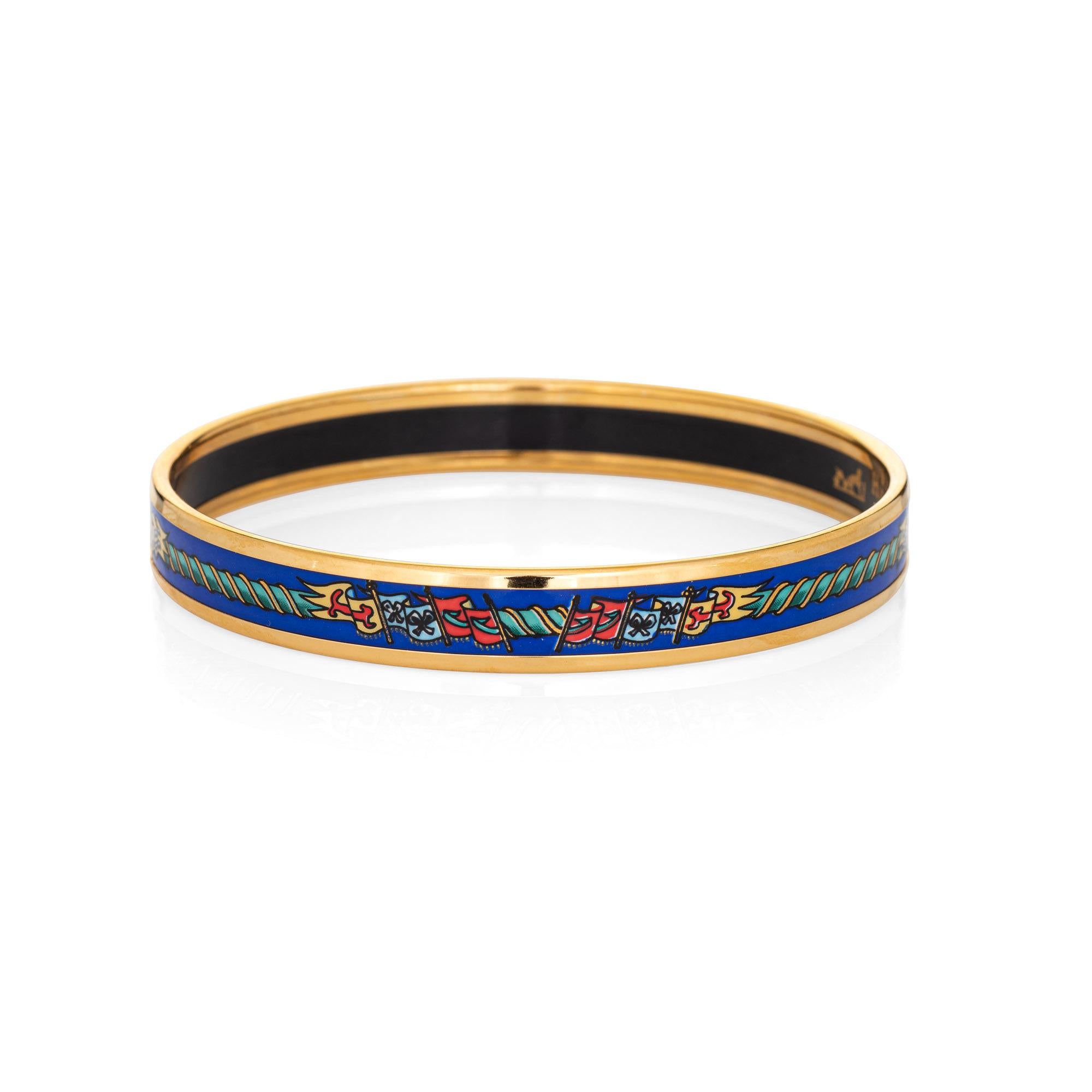 Overview:

Pre-owned vintage Hermes enamel bracelet with a pattern of colorful flags set upon a royal blue background, with yellow gold plated hardware.

The narrow 0.39