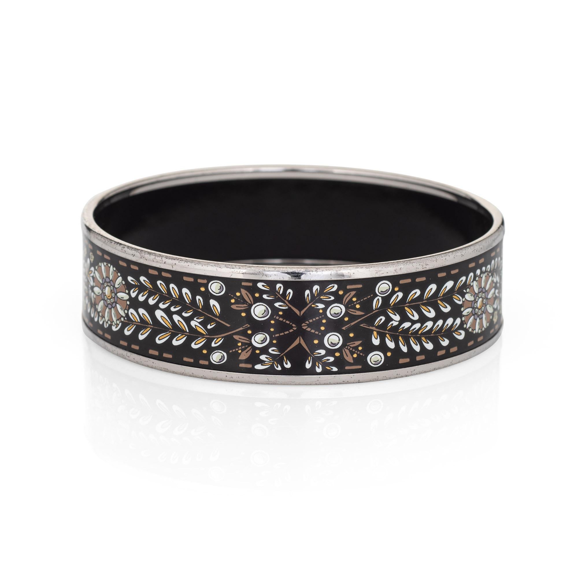 Overview:

Pre-owned vintage Hermes enamel bracelet with a black, white and gold printed flower design and palladium plated hardware.

The wide 0.79