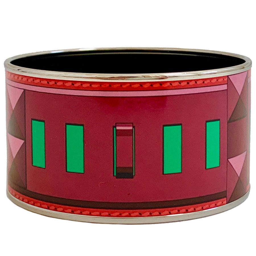 Manchette HERMES en émail rouge, violet et vert. Motif : collier de chien. Bordure en plaqué or.
Ce bracelet en émail n'a jamais été porté. Il y a néanmoins une petite trace près de l'inscription Made in France + Q (voir photo). Le chiffre 6 est