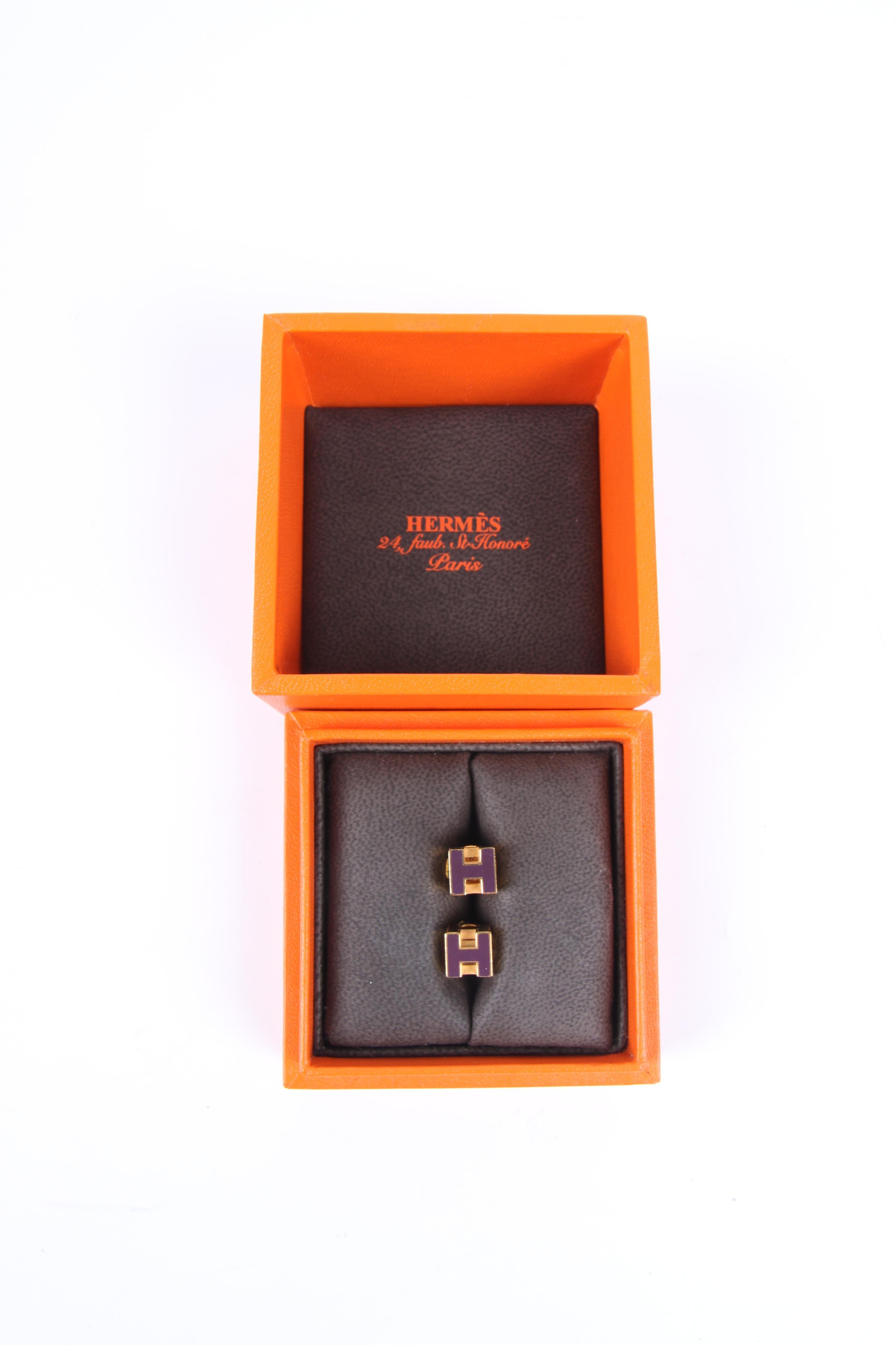 Sophisticated earrings by Hermès wearing the name Cage d'H, referring to the Hermès H's forming a cube.

At the front the H is enamelled in dark purple, on the top and bottom the H is executed in a gold-tone. Lovely round locking nuts embellished