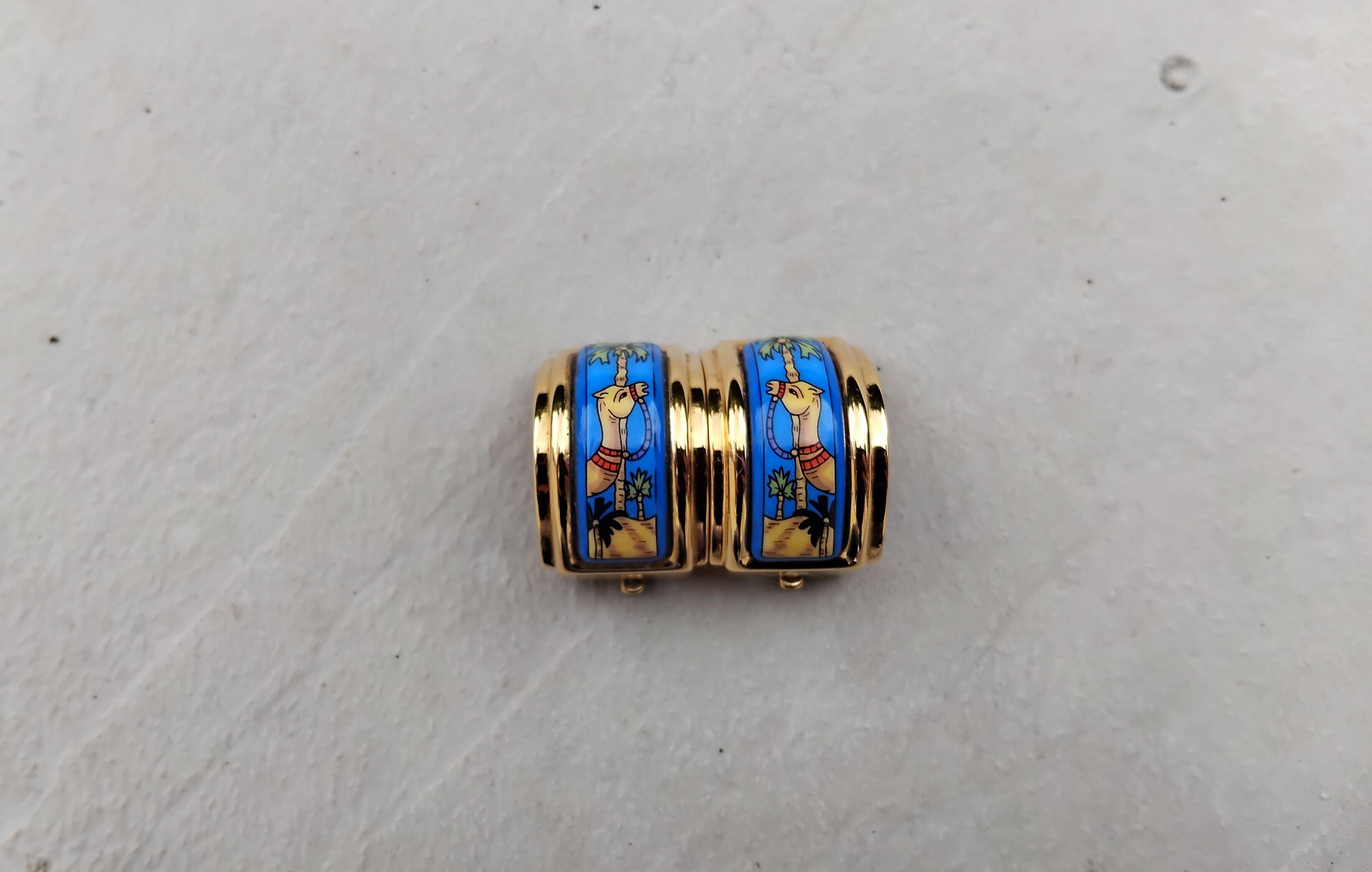 Magnifiques et rares boucles d'oreilles Hermès authentiques

Impression : Impression : chameaux, palmiers et sable du désert

Thème de l'Afrique

Fabriqué en émail imprimé et quincaillerie plaquée or jaune

Boucles d'oreilles à clipser : conviennent