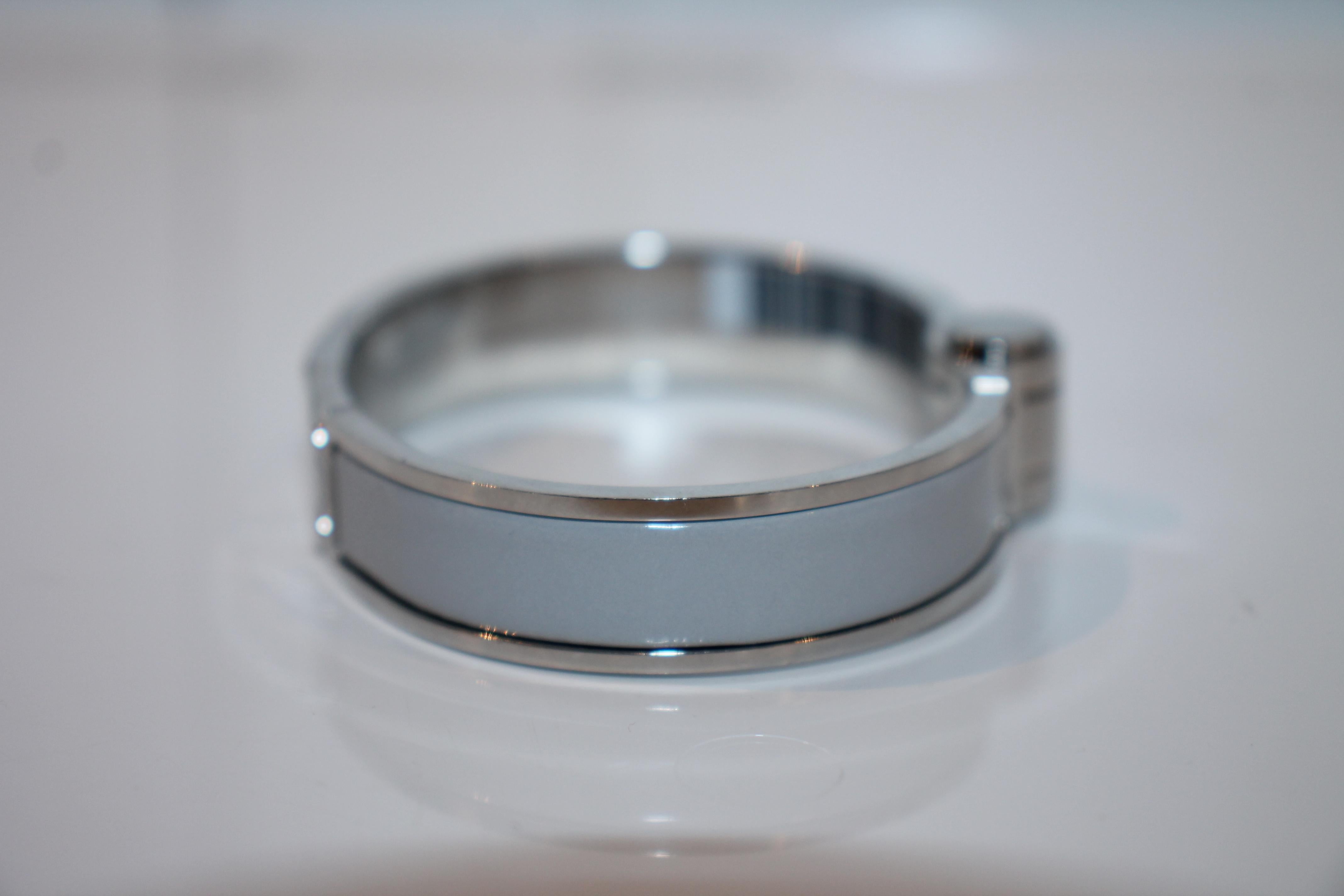 Palladium-plated Hermès oval hinged bracelet with an enamel inlay at a high polish finish with a hinged clip closure. (Size: 55)