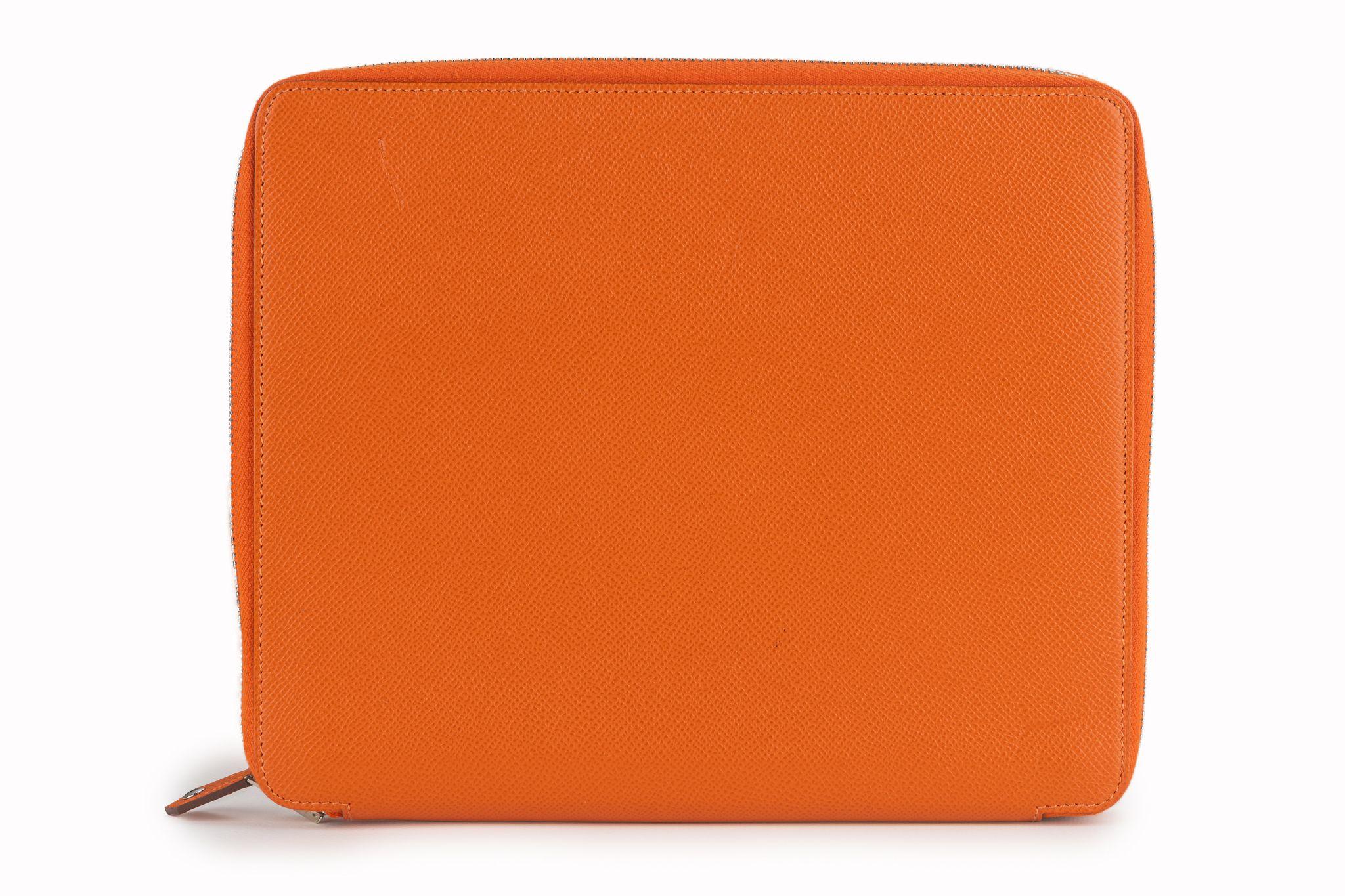 Esta funda Hermès Epsom E-Zip para iPad en naranja. Esta elegante funda está fabricada en piel de becerro de color naranja. La cremallera envolvente de paladio se abre a un interior a juego con bolsillos.