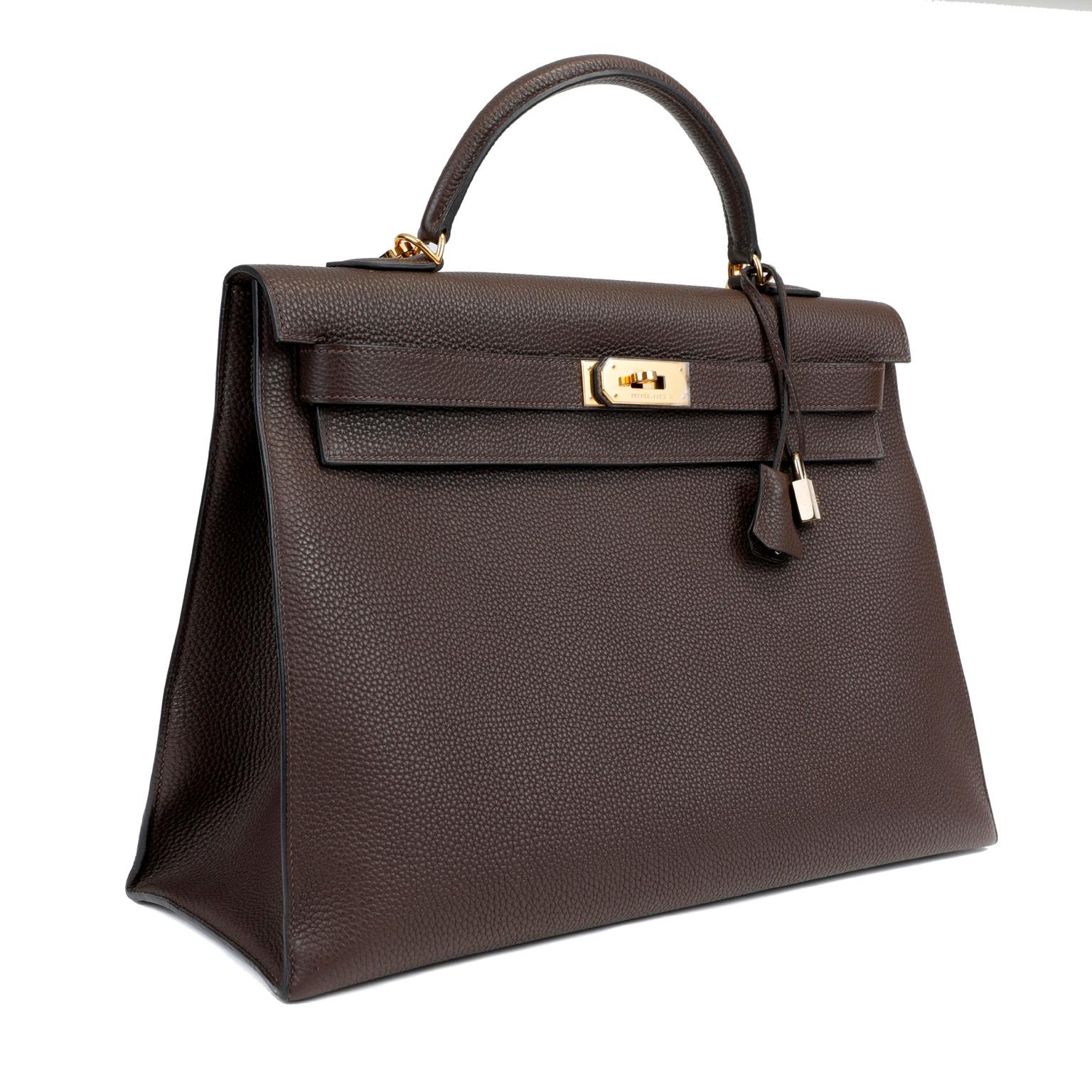 This authentic Hermès Espresso Brown Togo 40 cm Kelly is in pristine condition.  The protective plastic remains intact on the hardware.   Hermès bags are considered the ultimate luxury item worldwide.  Each piece is handcrafted with waitlists that
