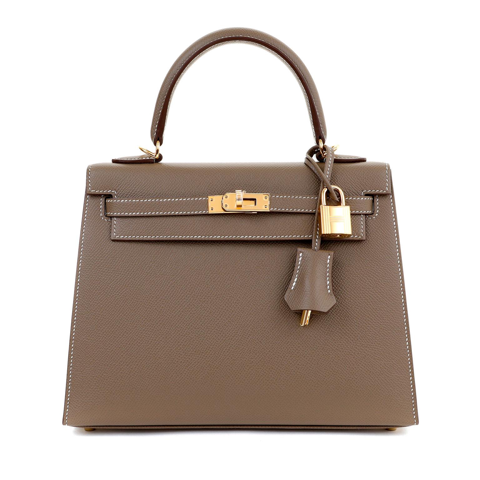 This authentic Hermès Etain Madame 25 cm Sellier Kelly is pristine with the protective plastic intact on the hardware.  Designed with the stitching on the outside of the bag, the Sellier silhouette has a more structured appearance than the Retourne