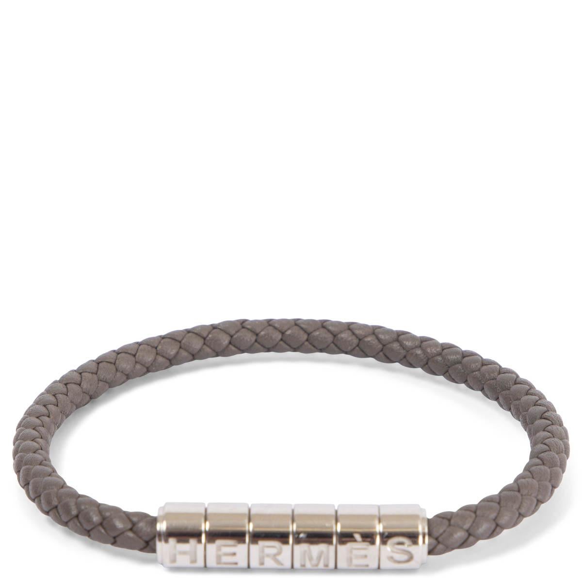 100% authentic Hermès Goliath Code bracelet in Etain grey braided Swift leather with palladium hardware. The bracelet's clasp plays on the five letters of Hermes like a secret code. Has been worn and is in excellent condition. Comes with