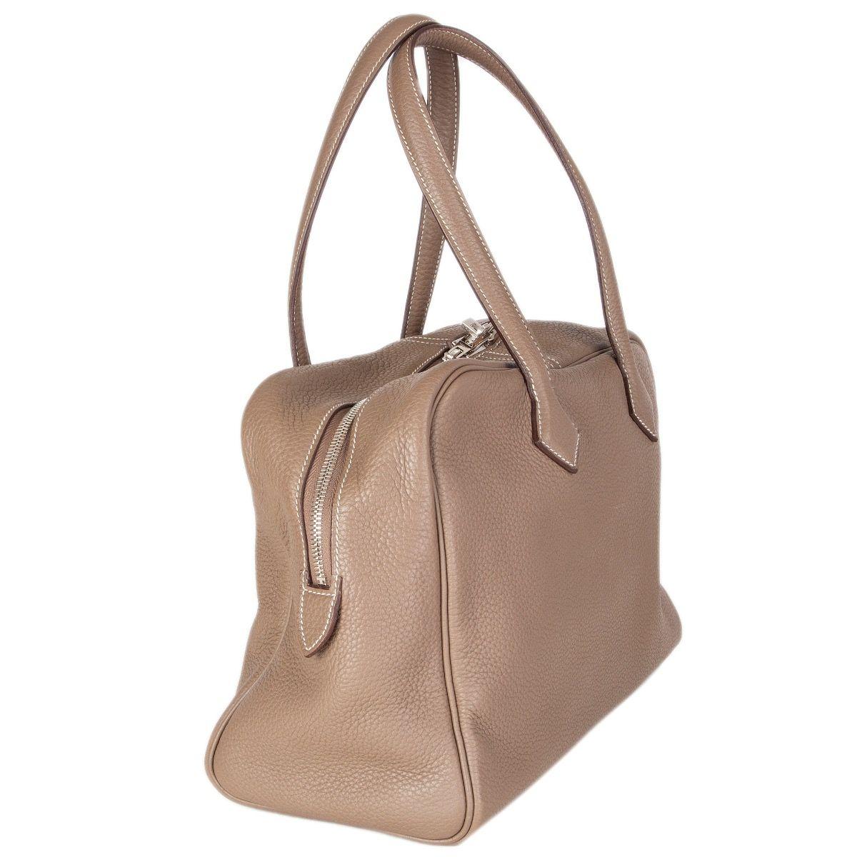 Hermes 'Victoria II Fourre-Tout 35' shoulder bag in Etoupe (taupe) Taurillon Clemence leather with contrasting white stitching. Closes with a two-way zipper on top. Lined in herringbone canvas with an open pocket against the front and two open