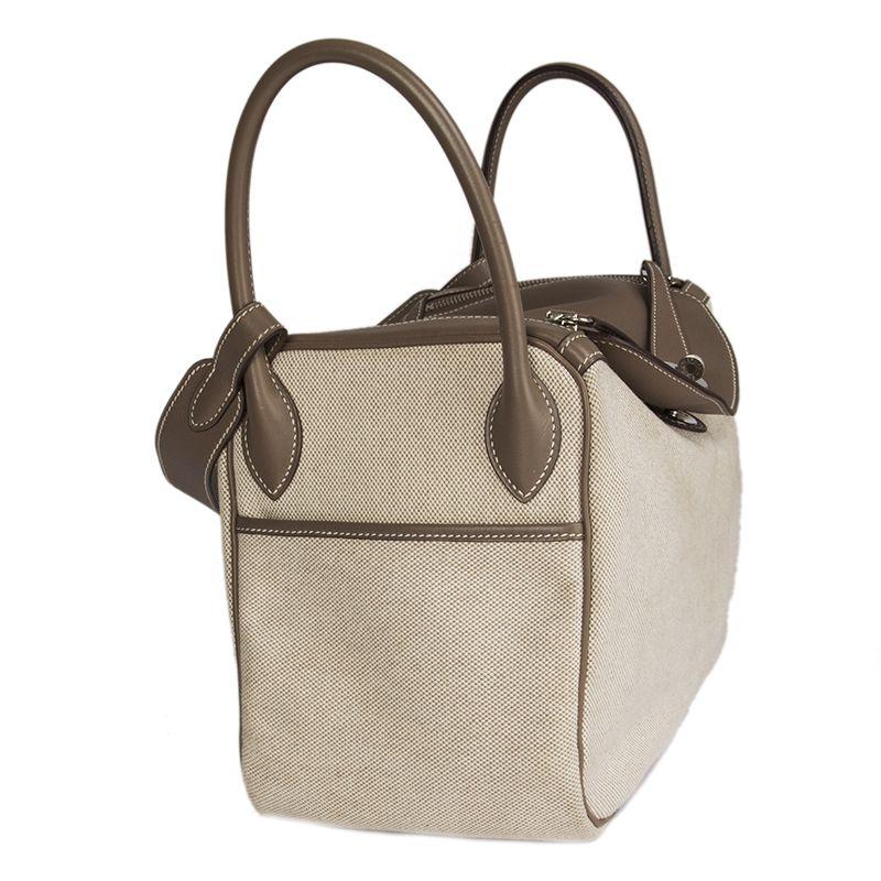 Hermes 'Lindy 30' in Etoupe Veau Swift leather (smooth) and off-white Toile H canvas. Outside pocket on each gusset. Closes with a zipper on top. Lined in canvas with an open pocket against the gussets. Has been carried and is in excellent