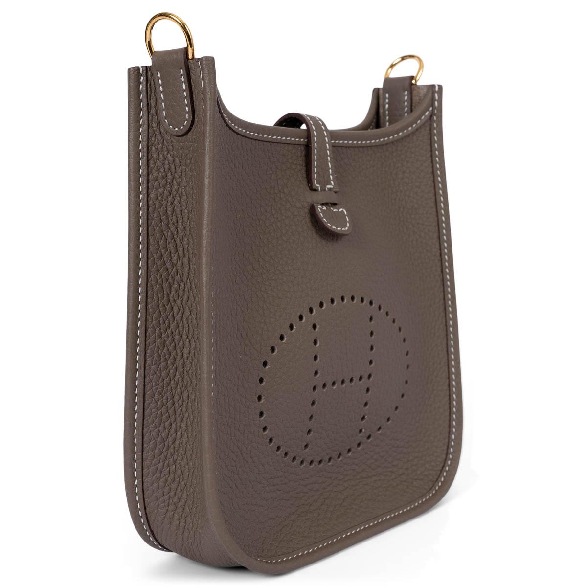 This 100% authentic Hermès Evelyne 16 TPM crossbody bag in Etoupe Taurillon Clemence leather is a refined everyday essential. Featuring the signature perforated 