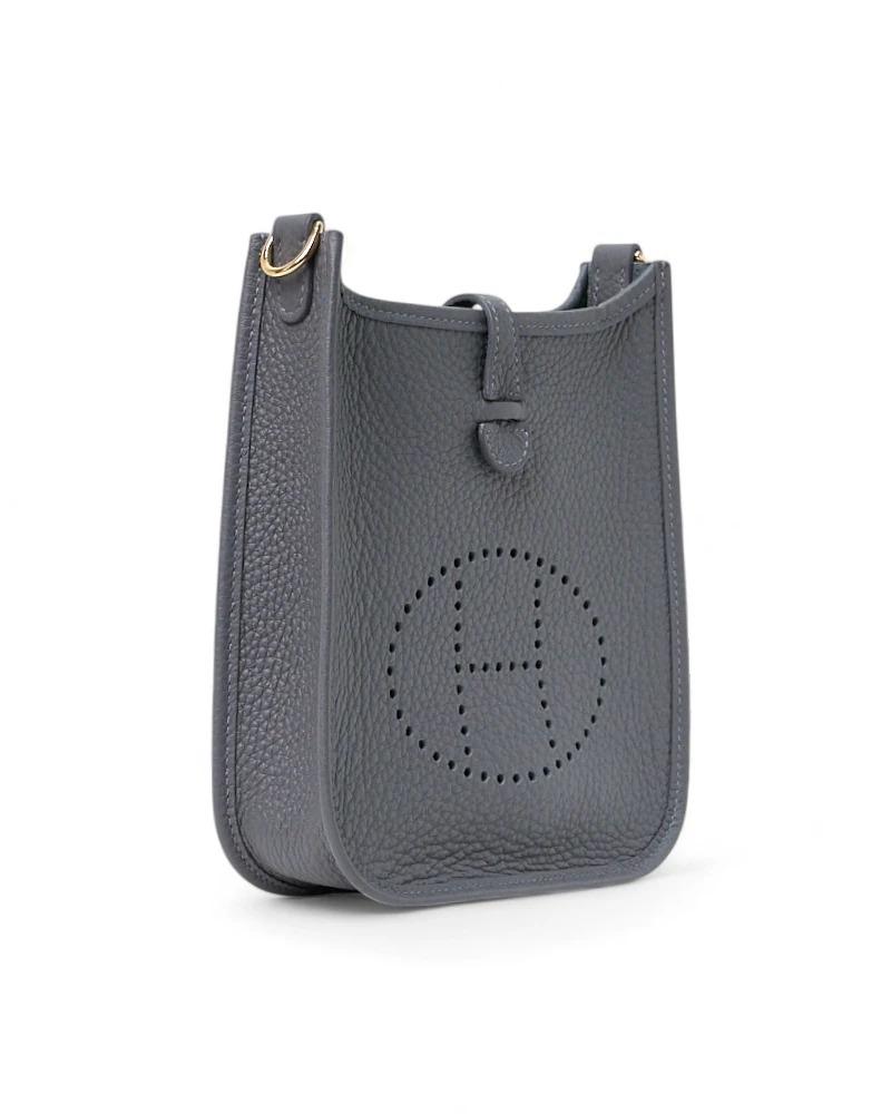 Borsa firmata Hermès, modello Evelyne nella misura 16, realizzata in pelle amazon nella sofisticata colorazione Ardoise Bleu Hydra. Dotata di una fascia con chiusura a clip, internamente rivestita in tessuto scamosciato tono su tono, la borsa è