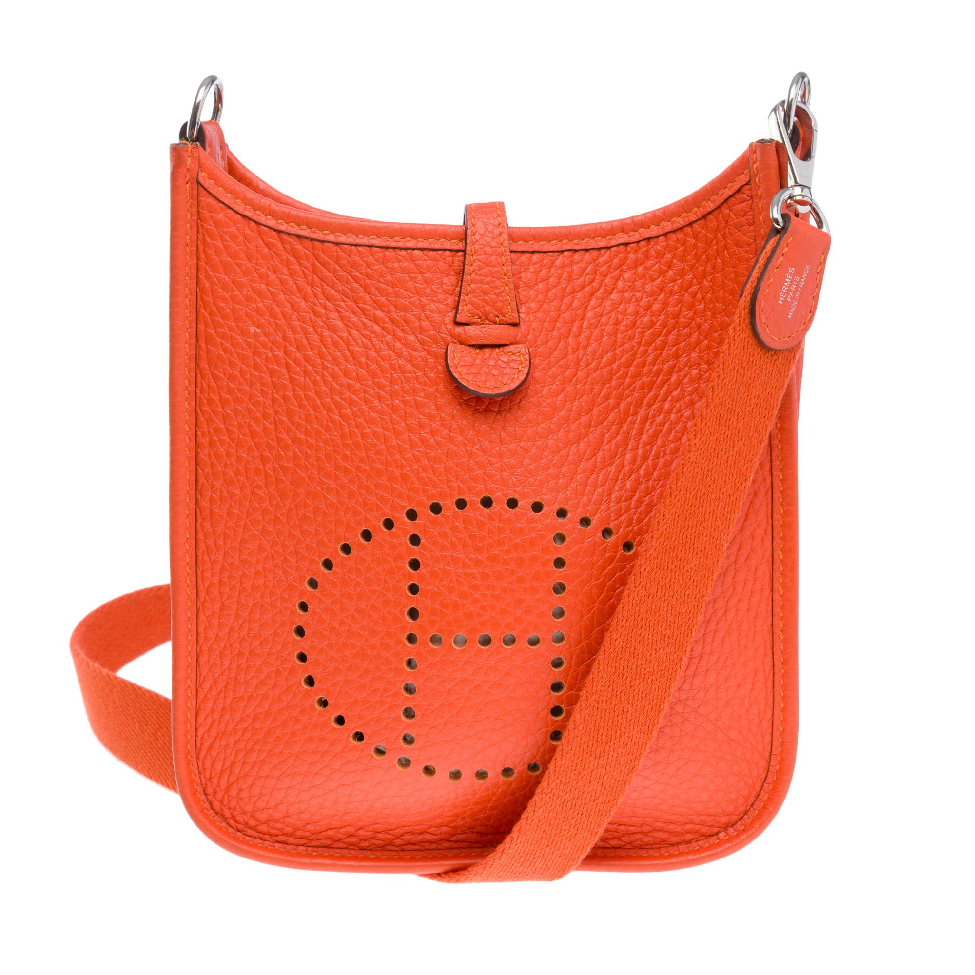 Wunderschöne Hermes Evelyne 16 TPM Taurillon Clémence Orange feu Leder, palladiumsilberne Metallbeschläge, ein abnehmbarer Schulterriemen aus orangefarbenem Stoff, der das Tragen über der Schulter oder als Crossbody ermöglicht

Schnappverschluss an