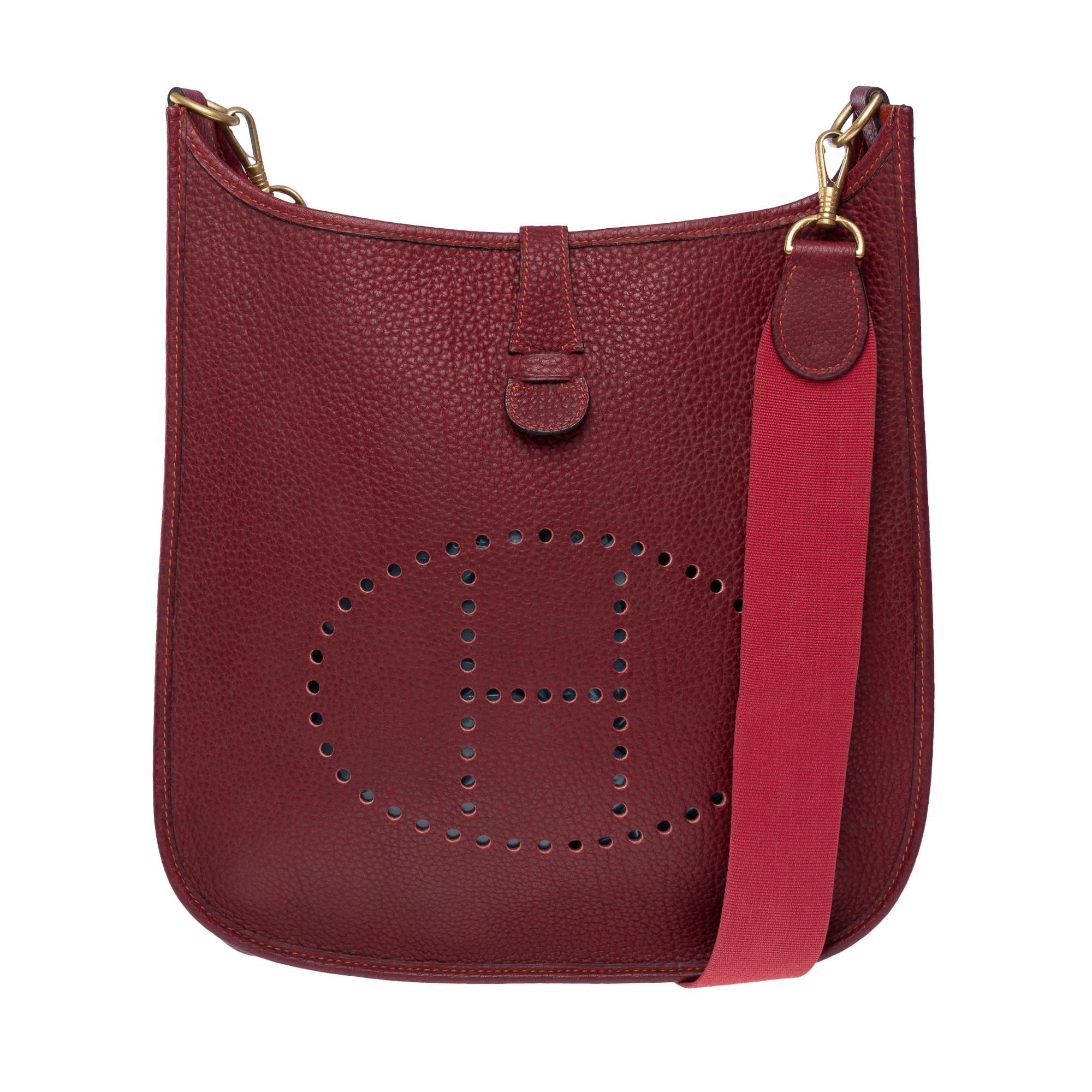 Iconic​ ​Hermès​ ​Evelyne​ ​GM​ ​shoulder​ ​bag​ ​in​ ​red​ ​Fjord​ ​leather,​ ​gold​ ​metal​ ​trim,​ ​a​ ​removable​ ​red​ ​canvas​ ​shoulder​ ​strap​ ​allowing​ ​for​ ​shoulder​ ​or​ ​crossbody​ ​carry

Closure​ ​with​ ​snap​ ​button​ ​on​
