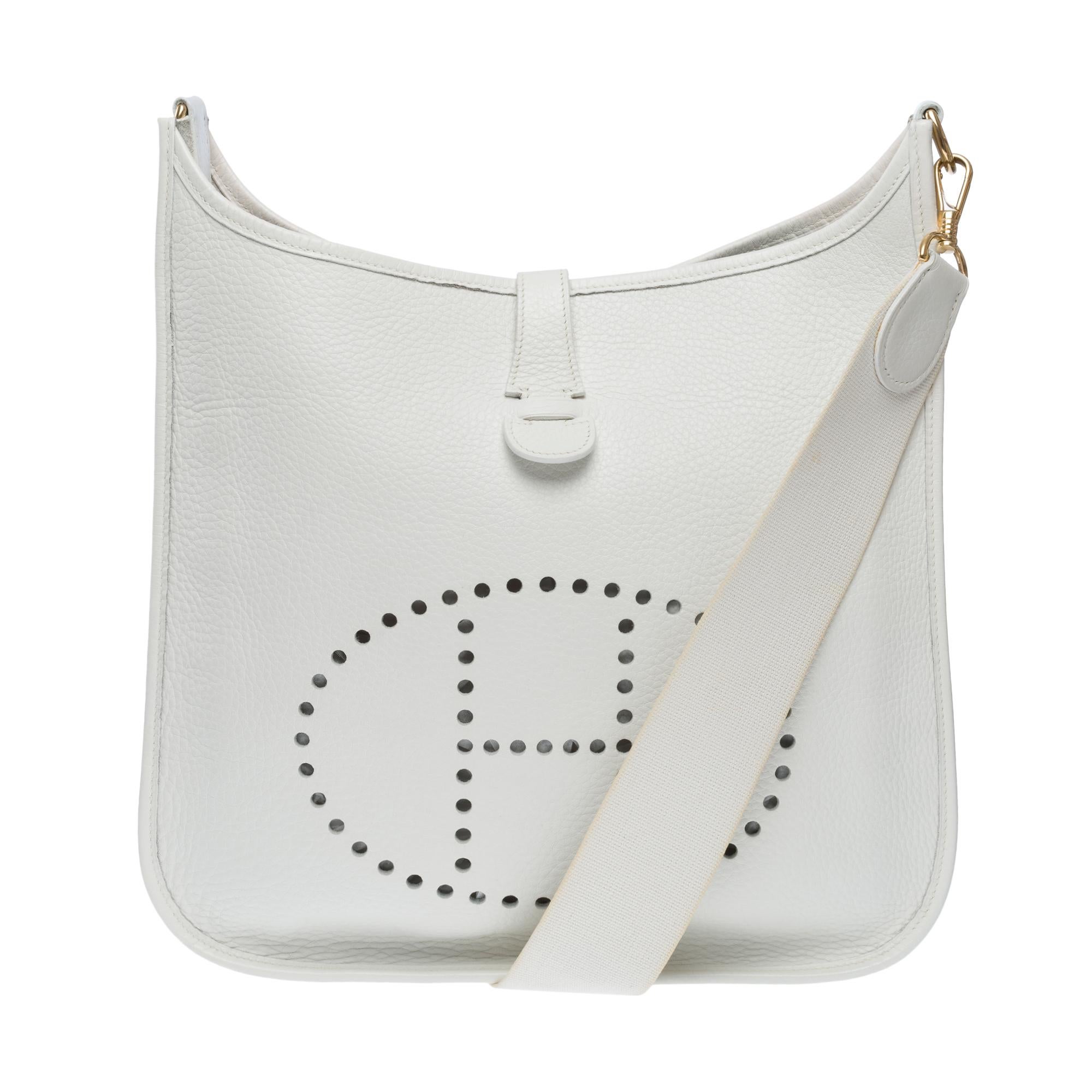 Iconic Hermes Evelyne GM shoulder bag in white Taurillon Clémence leather, gold metal trim, a removable shoulder strap in white canvas for shoulder or crossbody carry

Snap button closure on flap
Interior in white suede
Signature: 