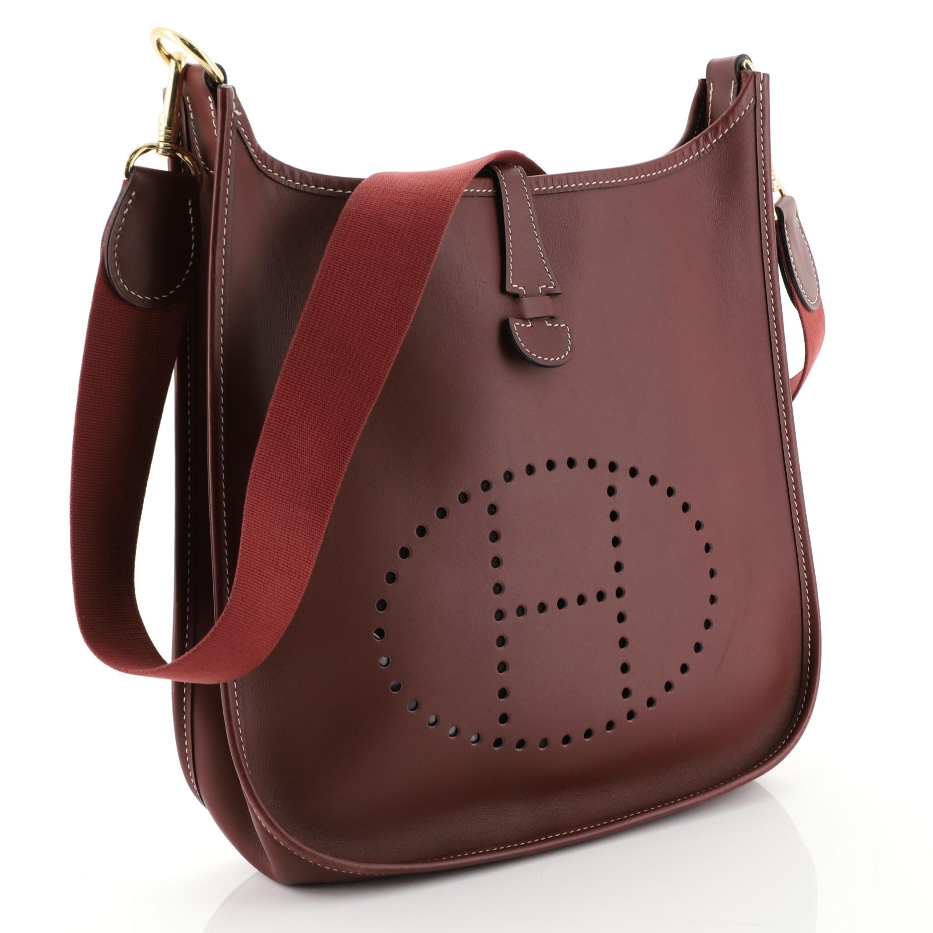 This Hermes Evelyne Crossbody Gen I Chamonix PM, crafted from Rouge H red Chamonix leather, features a signature perforated H design at the front, adjustable textile shoulder strap and gold-tone hardware. It opens to a red raw leather interior. Date