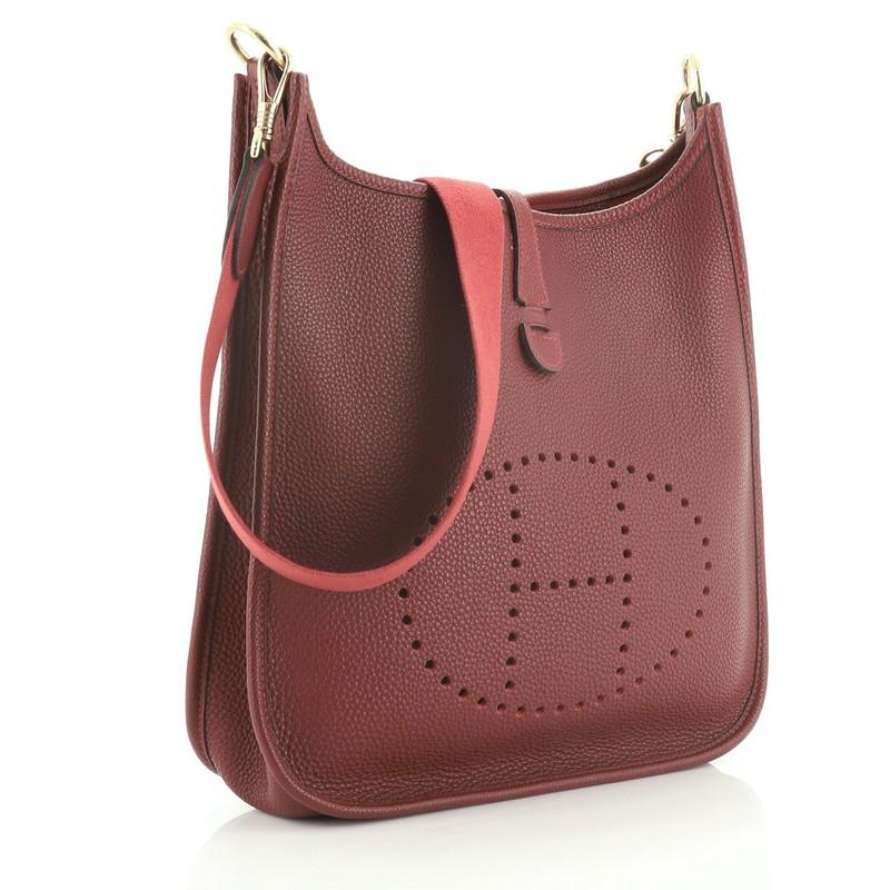 This Hermes Evelyne Crossbody Gen I Togo GM is an everyday bag that was originally designed in 1978 to hold horse grooming equipment. Crafted in Rouge H red Togo leather, this bag features perforated H design at the front, textile shoulder strap,
