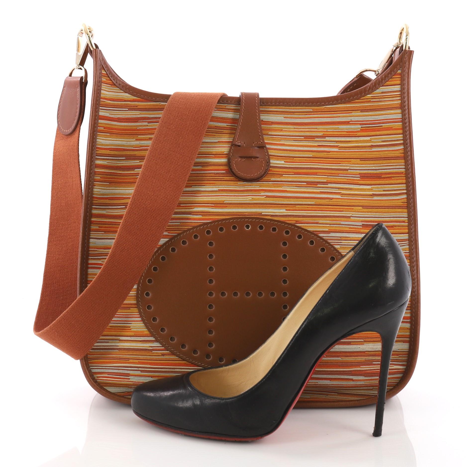 This Hermes Evelyne Crossbody Gen I Vibrato and Box Calf PM, crafted from brown multicolor vibrato and barenia, features a signature perforated H design at the front, textile shoulder strap, and gold-tone hardware. It opens to a brown leather