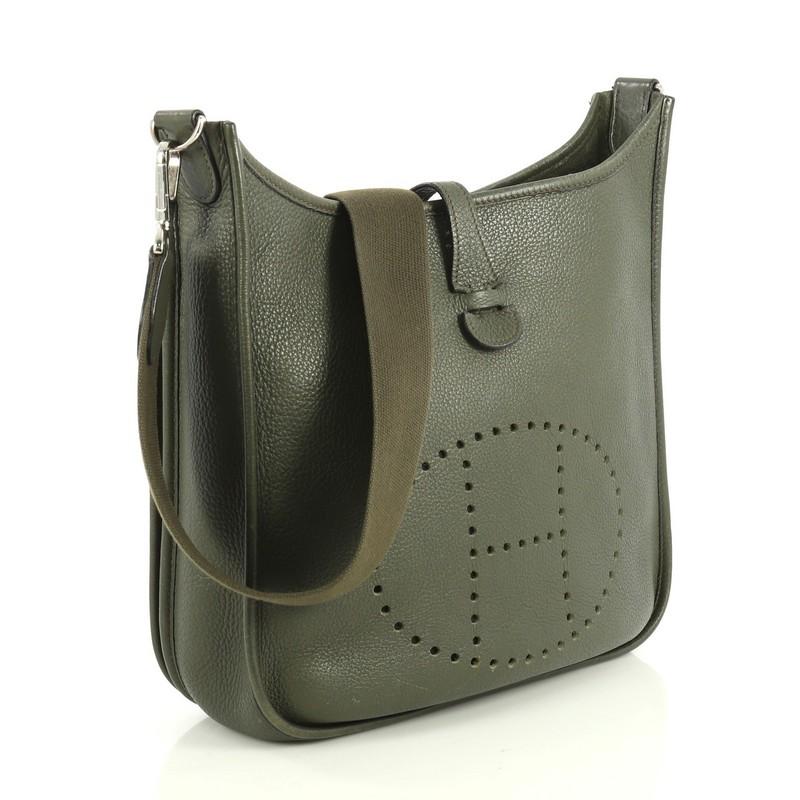 This Hermes Evelyne Crossbody Gen II Clemence PM, crafted in Vert Olive green Clemence leather, features a long crossbody strap, perforated H design at the front, and palladium hardware. Its top leather tab closure opens to a Vert Olive green raw