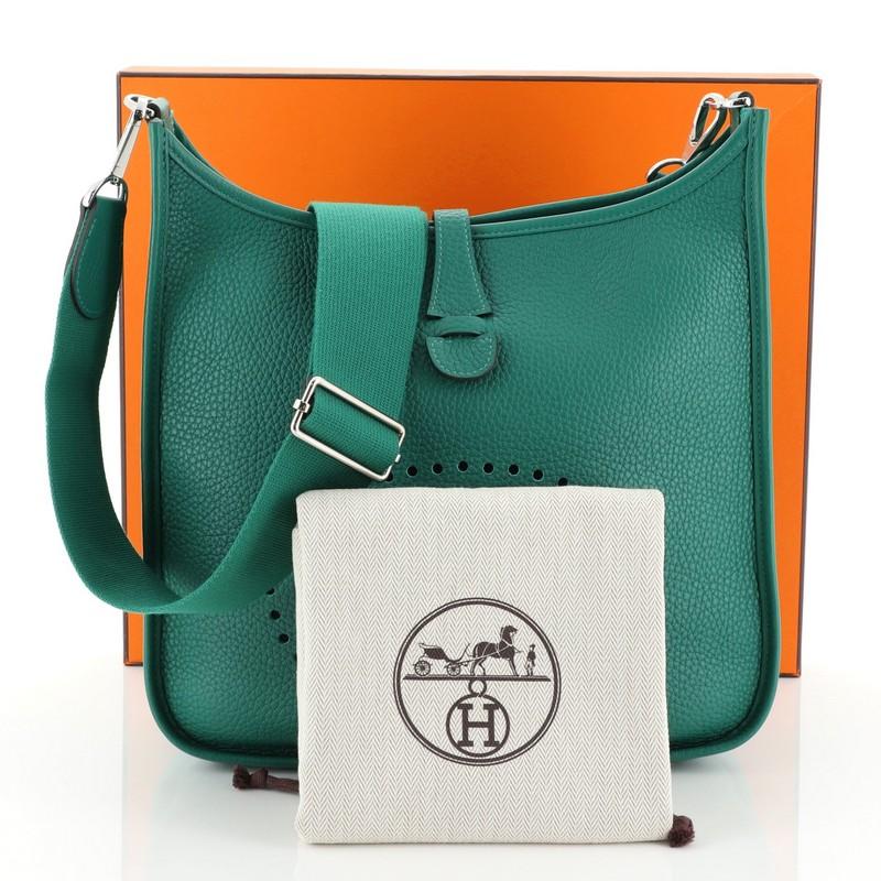 This Hermes Evelyne Crossbody Gen III Clemence PM, crafted in Vert Vertigo green Clemence leather, features perforated H design at the front, accessible back pocket, adjustable shoulder strap, and palladium hardware. It opens to a Vert Vertigo green