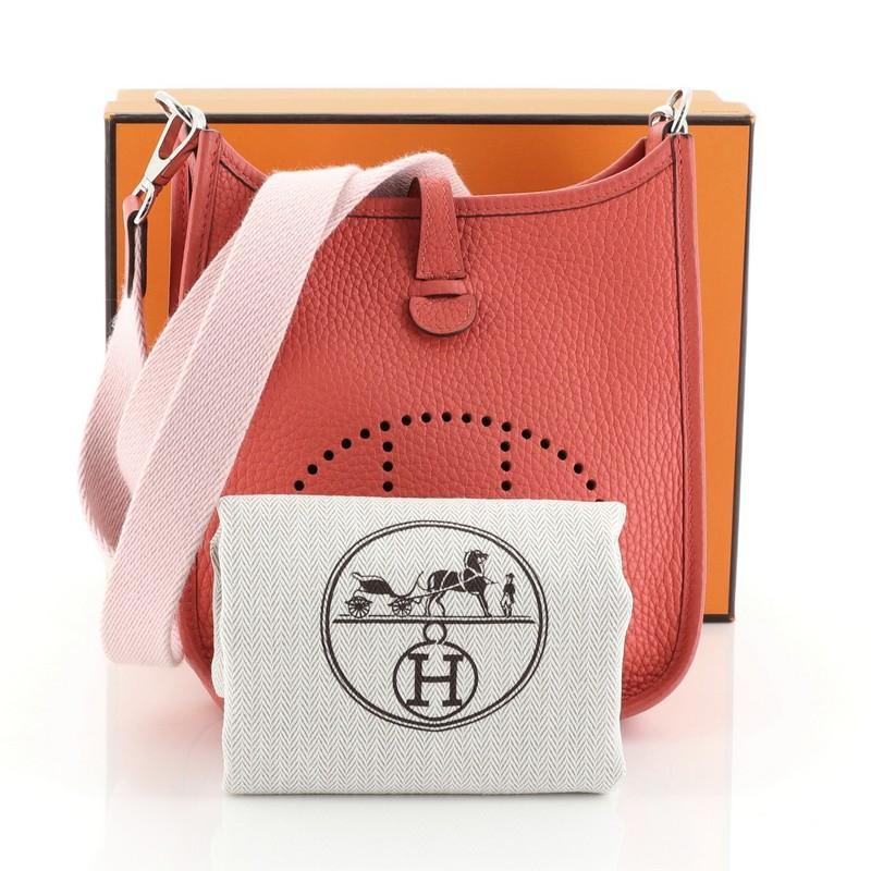 This Hermes Evelyne Crossbody Gen III Clemence TPM, crafted in Rouge Pivoine Clemence leather, features a signature perforated H design at the front, Rose Sakura Amazone shoulder strap and palladium hardware. It opens to a Rouge Pivoine raw leather