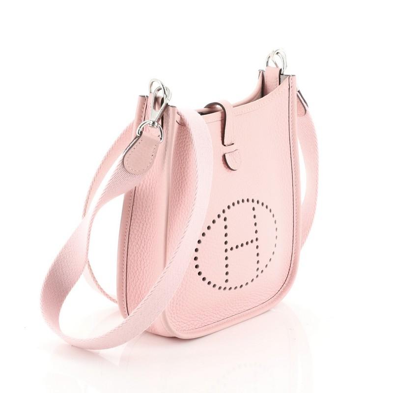 This Hermes Evelyne Crossbody Gen III Clemence TPM, crafted in Rose Sakura pink Clemence leather, features perforated H design at the front, textile shoulder strap and palladium hardware. It opens to a Rose Sakura pink raw leather interior. Date