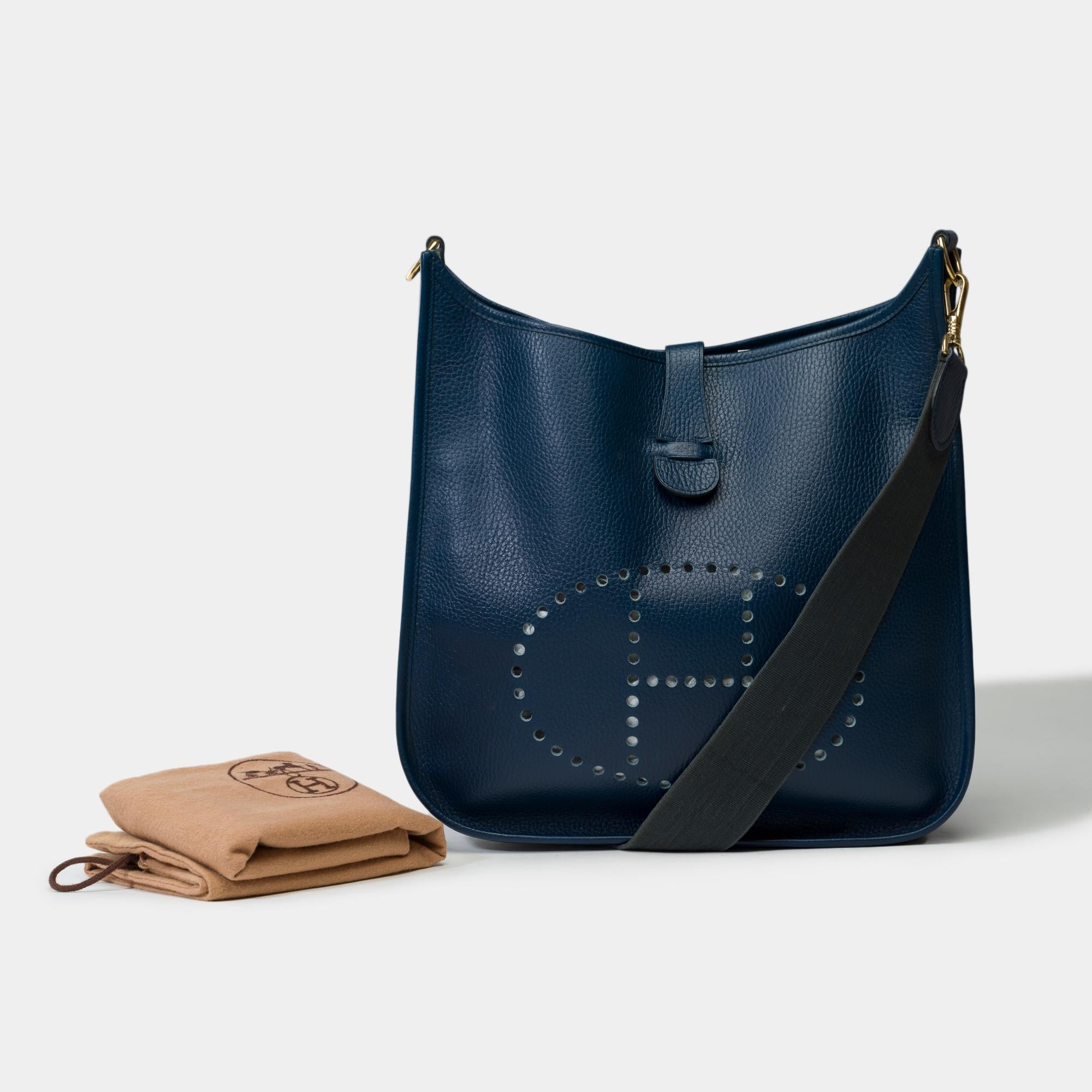 Iconic Hermès Evelyne GM shoulder bag in Navy blue Taurillon leather , gold metal trim, a removable shoulder strap in blue canvas allowing a shoulder or crossbody carry

Snap button closure on flap
Interior in blue suede
Signature: 
