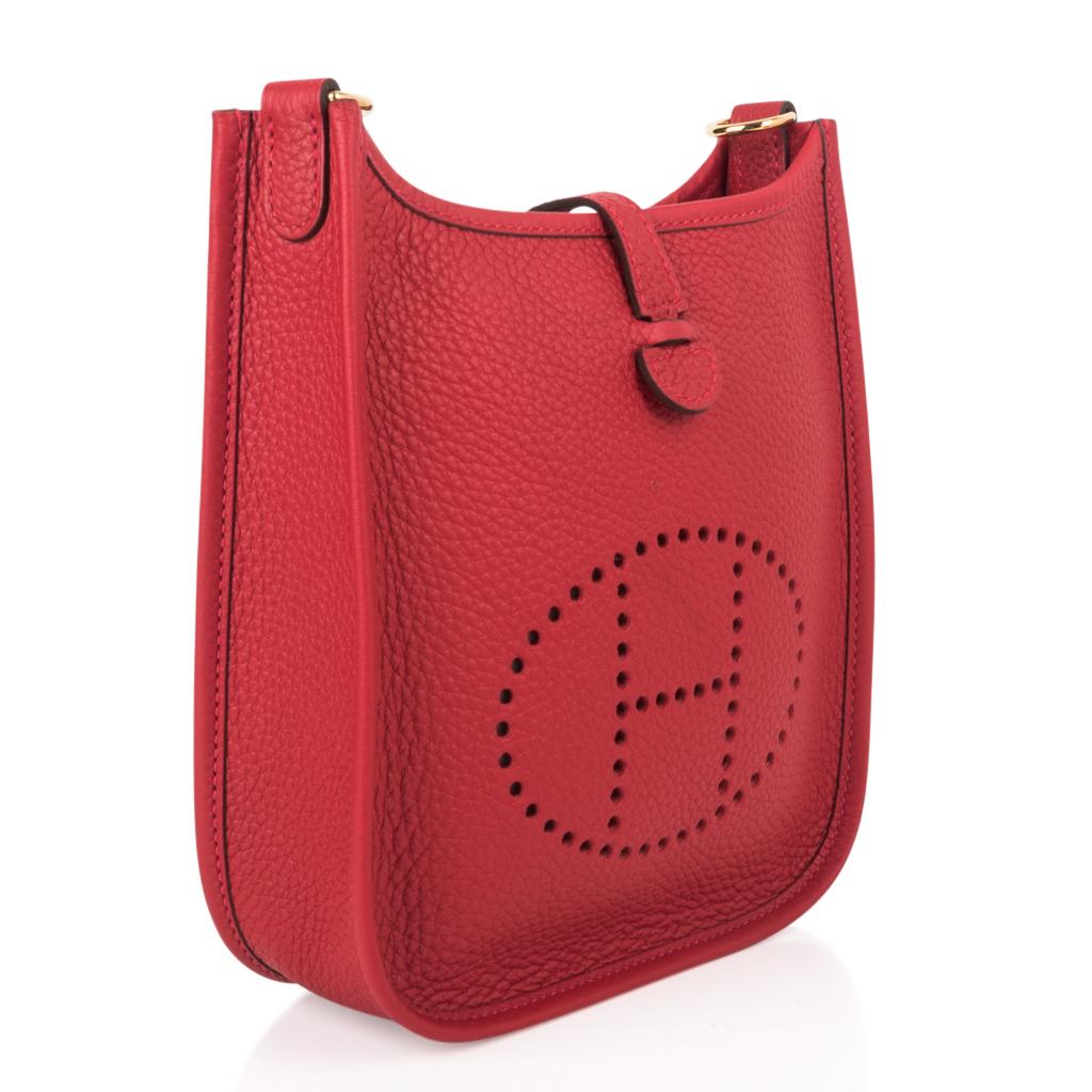 Guaranteed authentic rich Rouge Casaque Hermes Evelyne TPM bag.  
Clemence leather which is soft and scratch resistant. 
Sport canvas body strap is crisp and clean with rare gold hardware.
Signature perforated H on front of bag.
Fabulous shoulder or