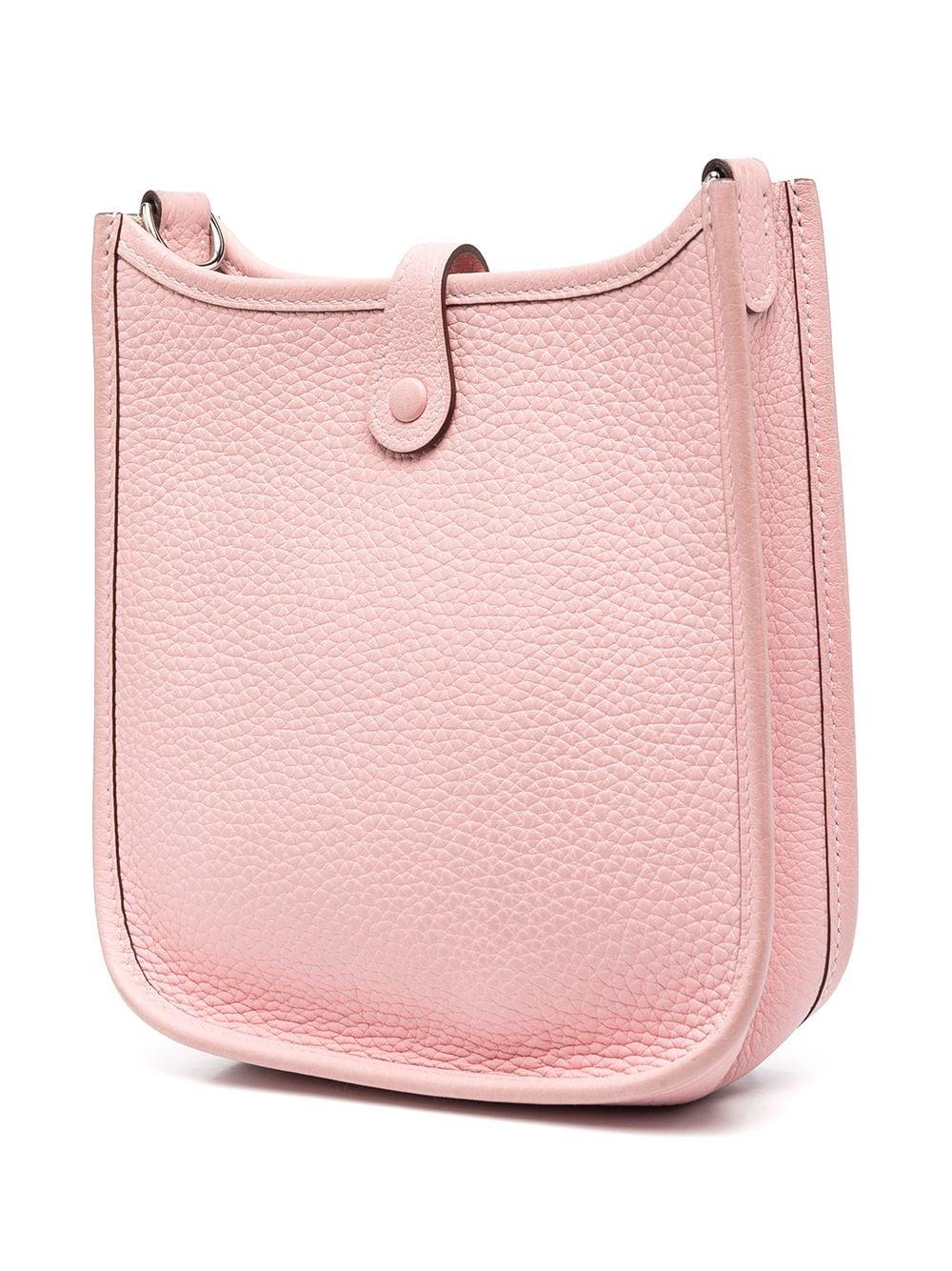 Crafted in a dreamy shade of pink (Pink Sakura) in Togo leather and Palladium hardware, this TPM Evelyne bag by Hermes remains stylish, functional and contemporary in a refined saddle-like shape with a perforated H logo decorating the front. The bag