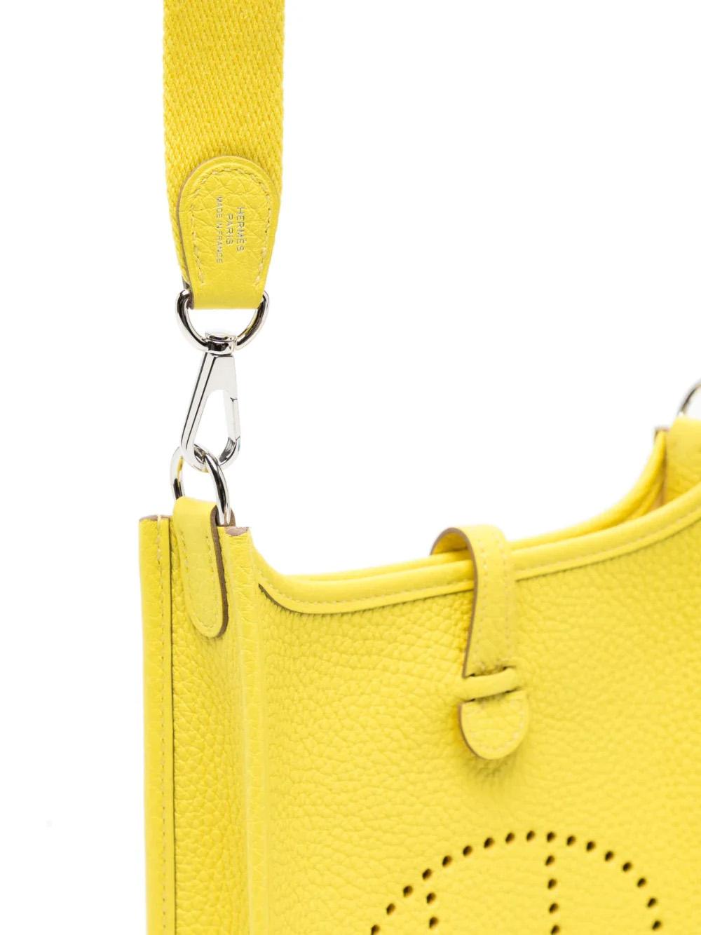 This is a timeless shoulder bag originally designed by Evelyne Bertrand in 1978. Crafted with yellow leather, the bag features the signature perforated H logo and palladium-plated hardware. Offering a press-stud fastening, main compartment, and an