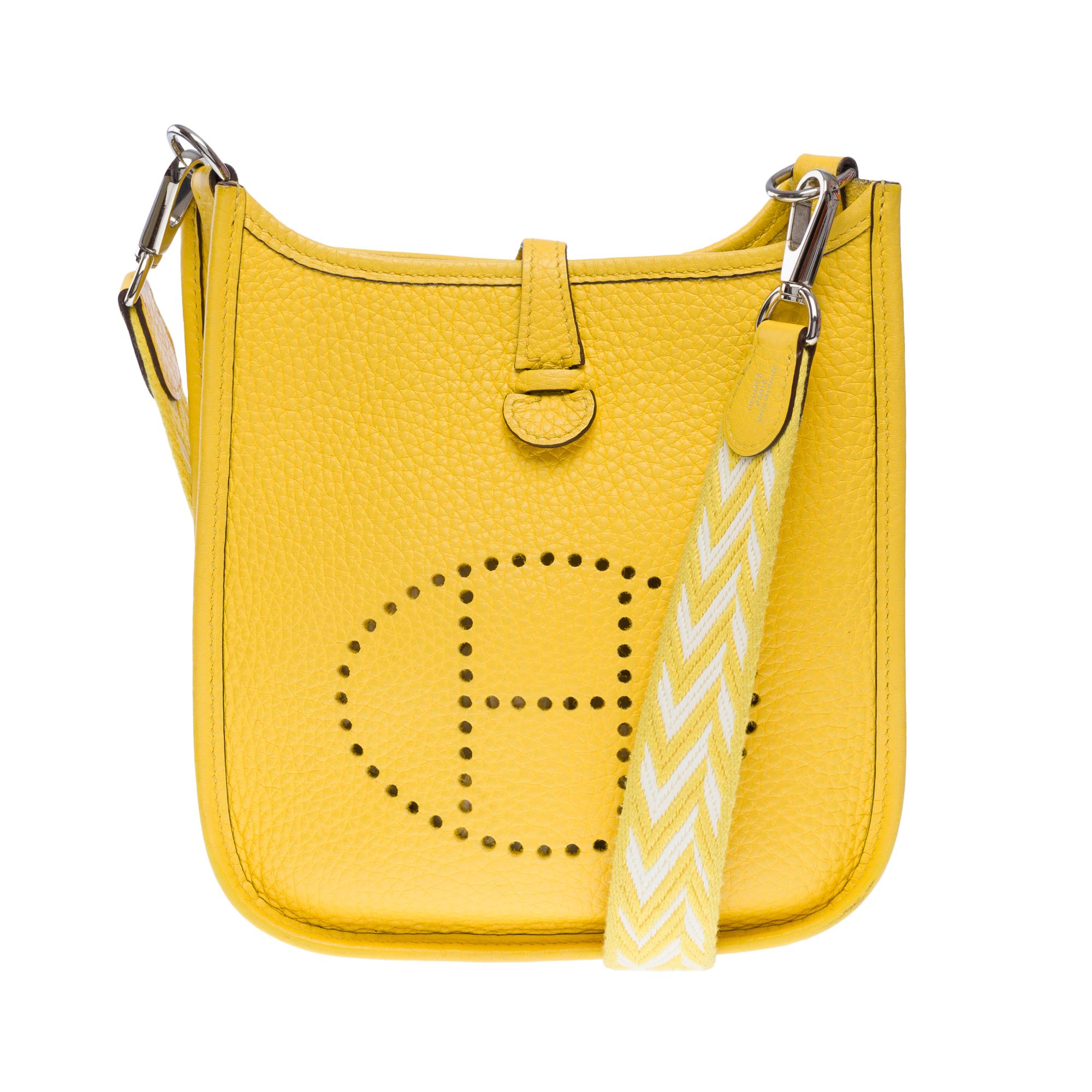 Bellissima borsa a tracolla Hermes Evelyne 16 TPM Zigzag in pelle Jaune de Naples Taurillon Clémence con finiture in metallo color argento palladio, una tracolla rimovibile in tela bianca e gialla a zig zag che permette di portarla a spalla o