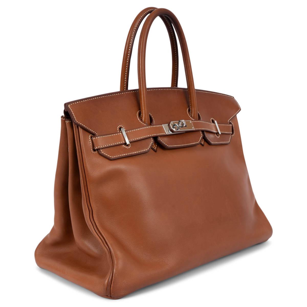 100% authentique Sac Hermès Birkin 35 en cuir Veau Barenia Fauve (marron cognac) avec accessoires Palladium. Doublé en Chevre (peau de chèvre) avec une poche ouverte sur le devant et une poche zippée au dos. Elle a été portée et présente une patine