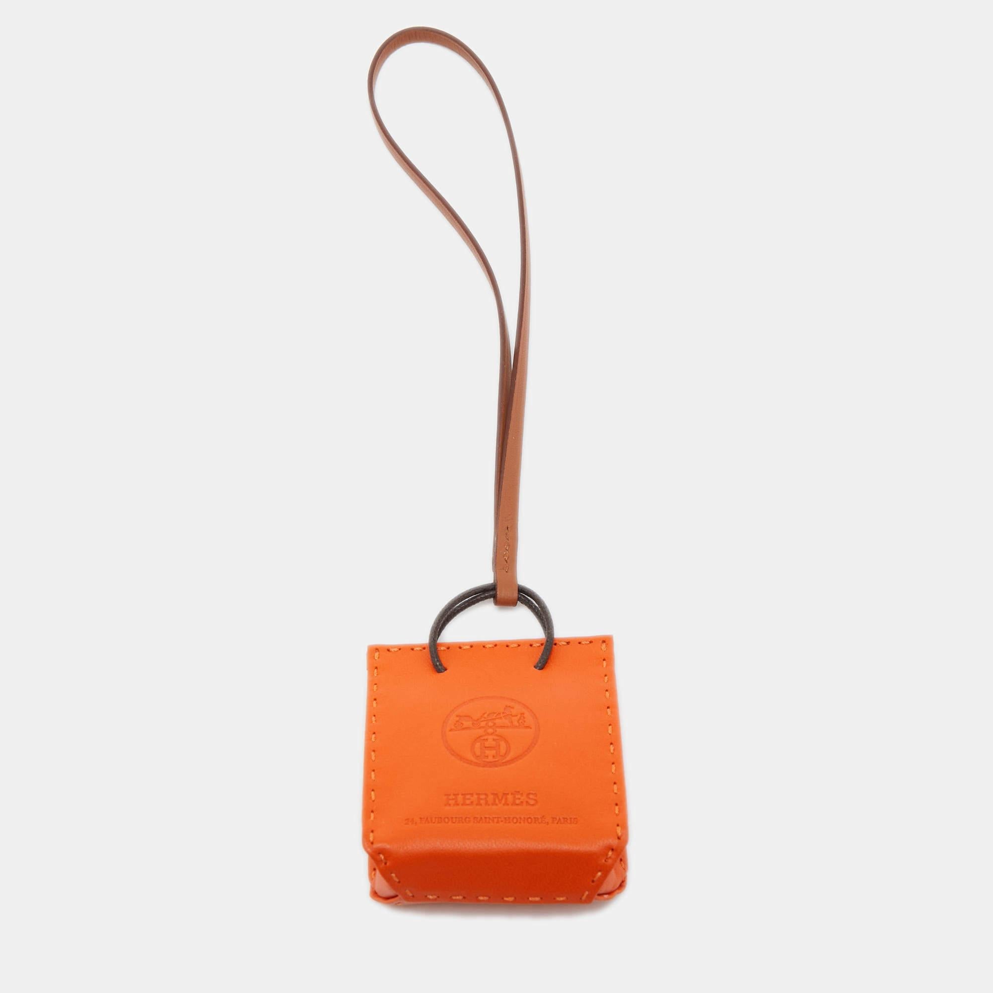 Lend your bag a luxe makeover with this stunning Hermes shopping bag charm. It is cut from leather in the shape of a bag and is held by a strap.

