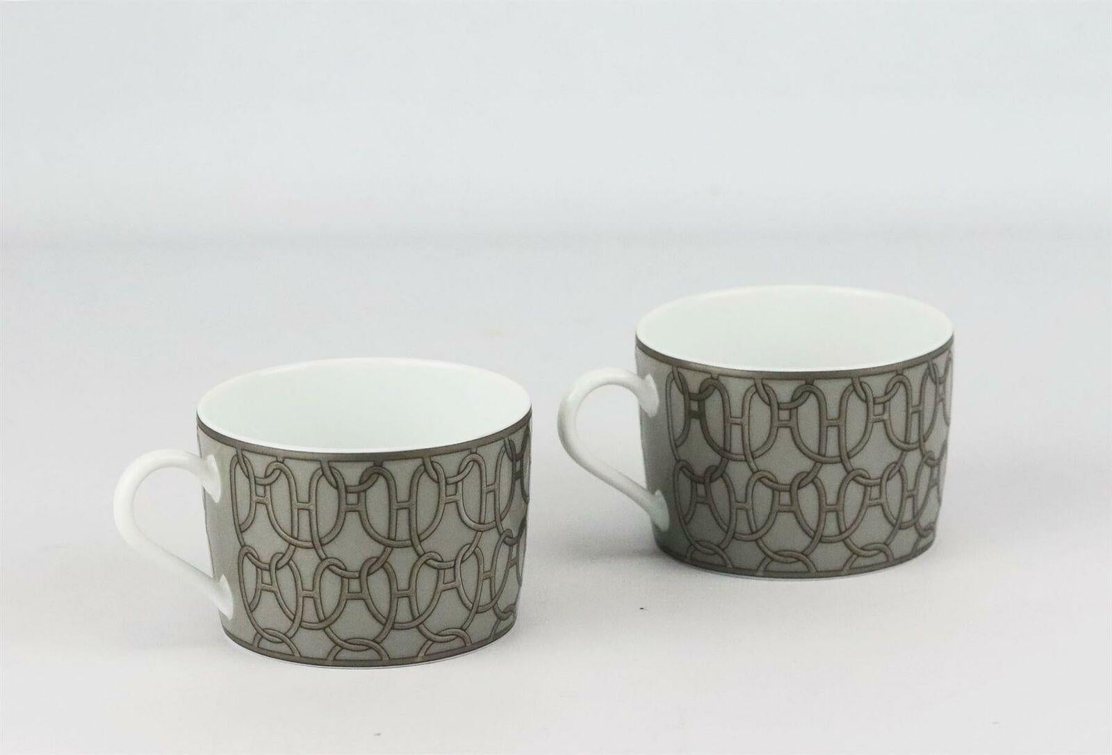 Set di 2 tazze da colazione in porcellana grigia, argento e bianca di Hermès Fil d'Argent con design a catena, accenti dorati e timbro del marchio sul fondo.
Non viene fornito con la scatola.

Dimensioni: H. 2,25 x P. 3 pollici.
Sono disponibili