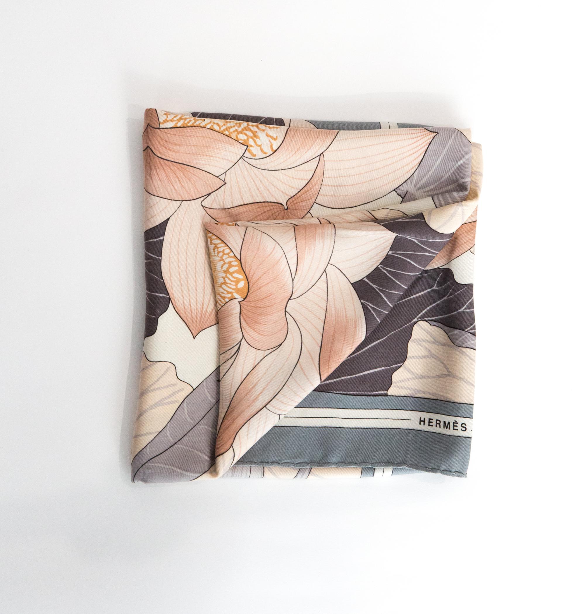Hermes « Fleur de lotus » by Christiane Vauzelles silk scarf featuring a grey border and a Hermès signature. 
Circa 1976
In good vintage condition. Made in France.
35,4in. (90cm)  X 35,4in. (90cm)
We guarantee you will receive this  iconic item as